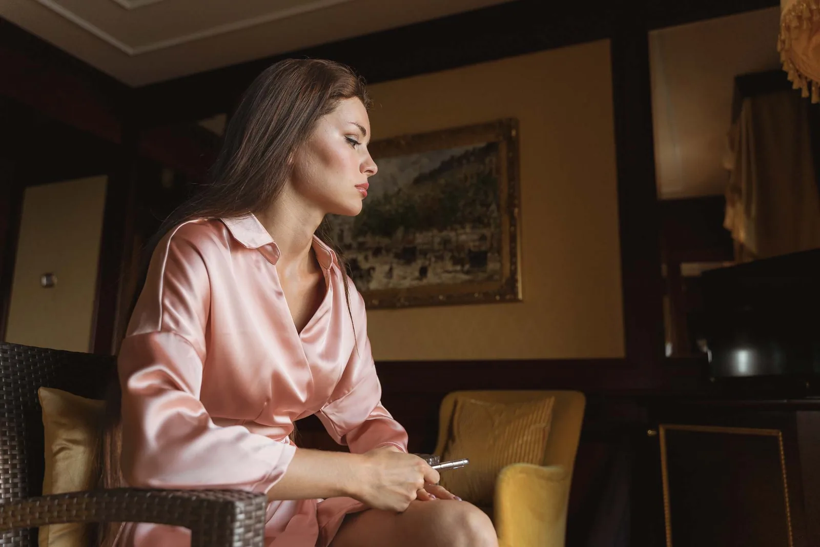 La sposa in vestaglia rosa, seduta tra i legni scuri della camera