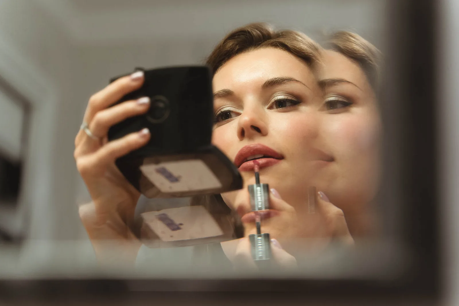 Il rossetto della sposa riflesso nello specchio, tra le dita
