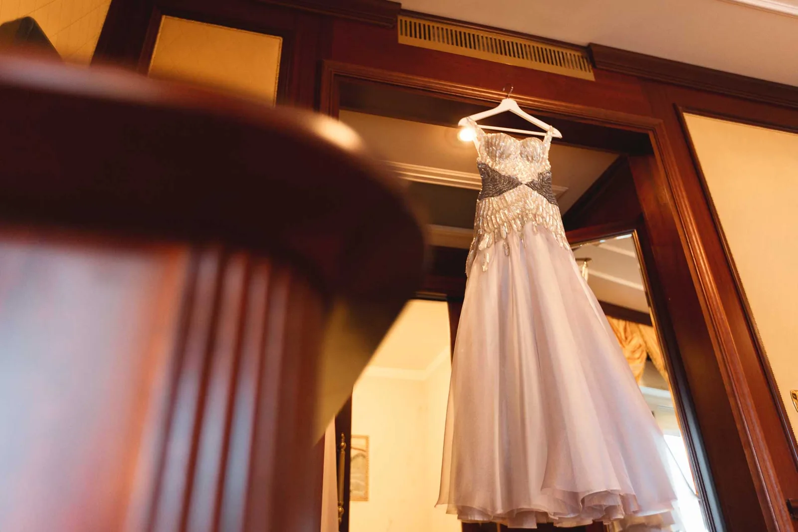 L'abito da sposa appeso oltre lo stipite in legno della camera