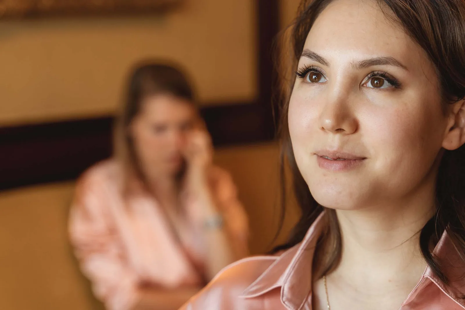 Un'amica in primo piano, assorta, con un'altra ragazza sullo sfondo