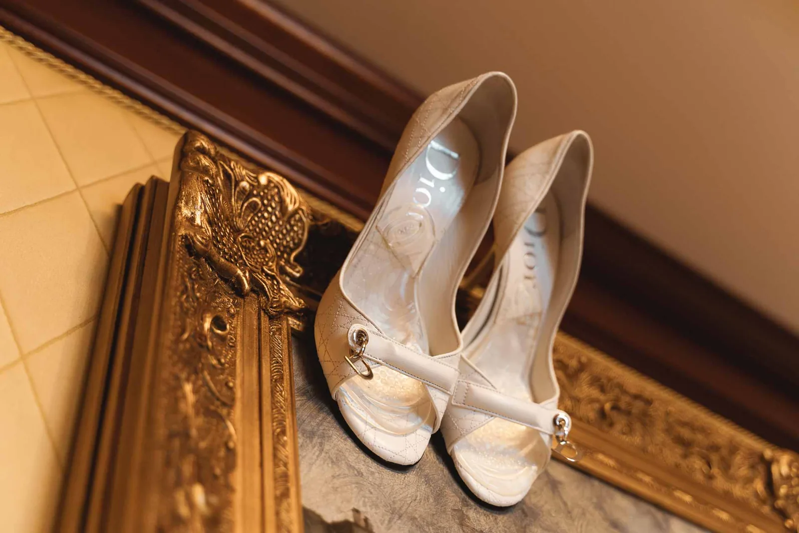 Le scarpe della sposa appoggiate sulla cornice dorata