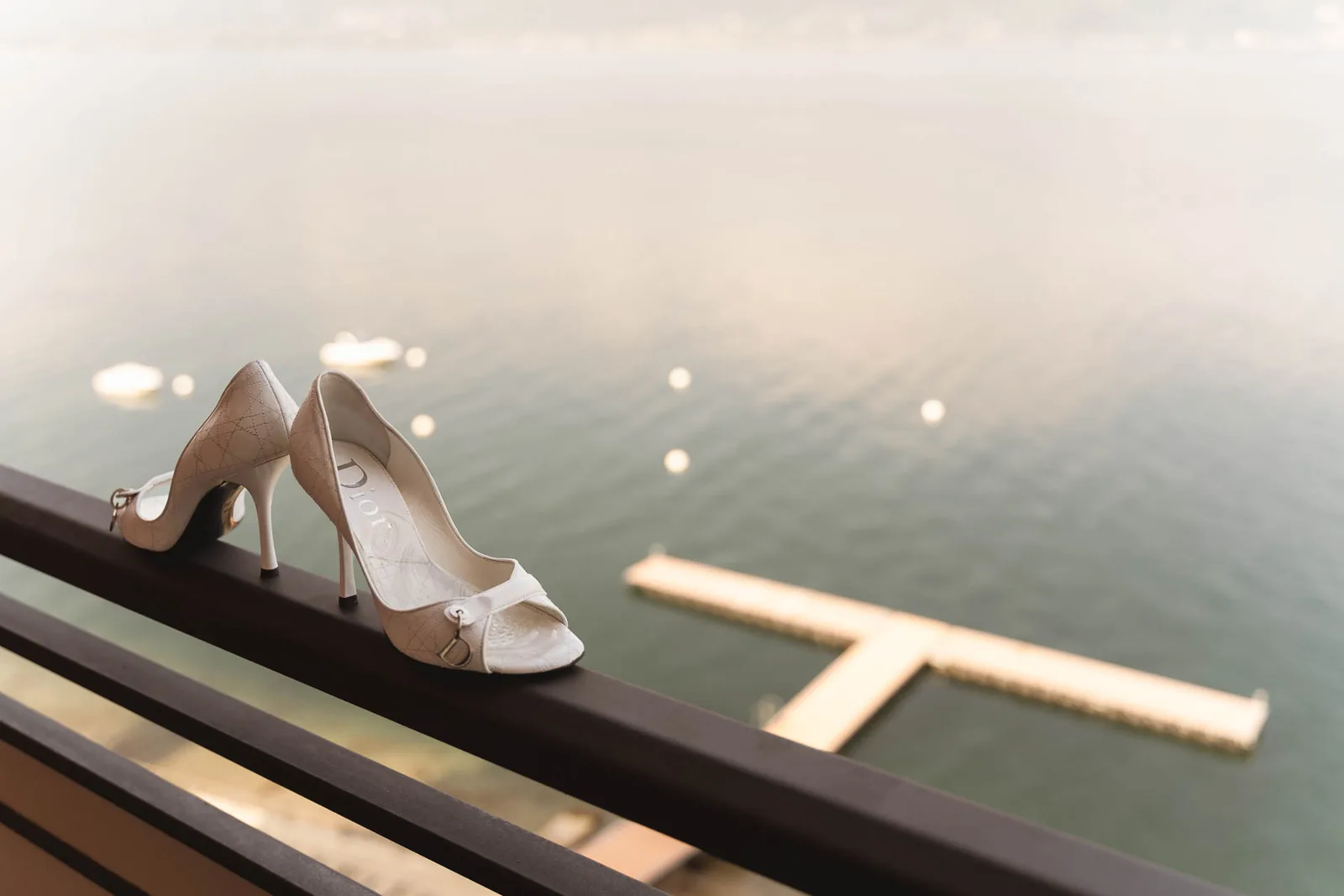 Le scarpe della sposa sulla ringhiera del balcone, sopra il Lago Maggiore e il pontile dell'albergo
