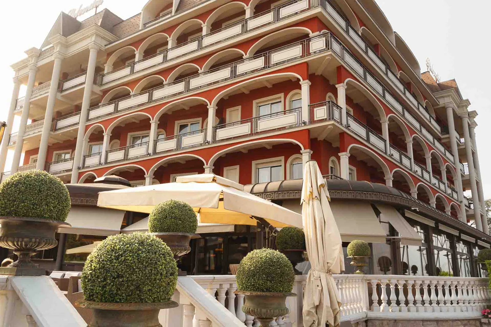 La facciata rossa dello Splendid Hotel con le logge bianche e le siepi potate a sfera