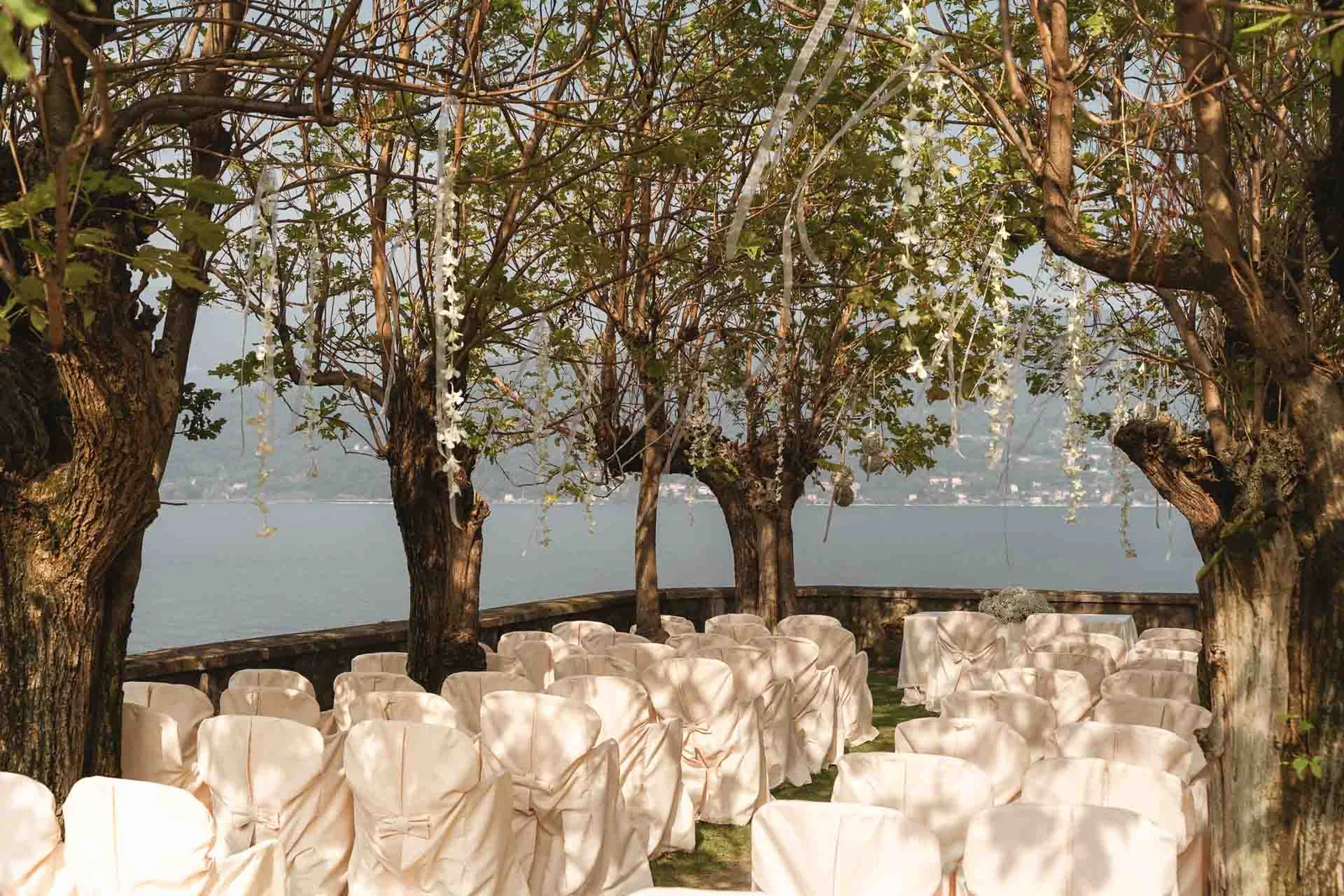 Le sedie bianche della cerimonia sotto gli alberi, in riva al lago, nel giardino dello Splendid Hotel di Baveno