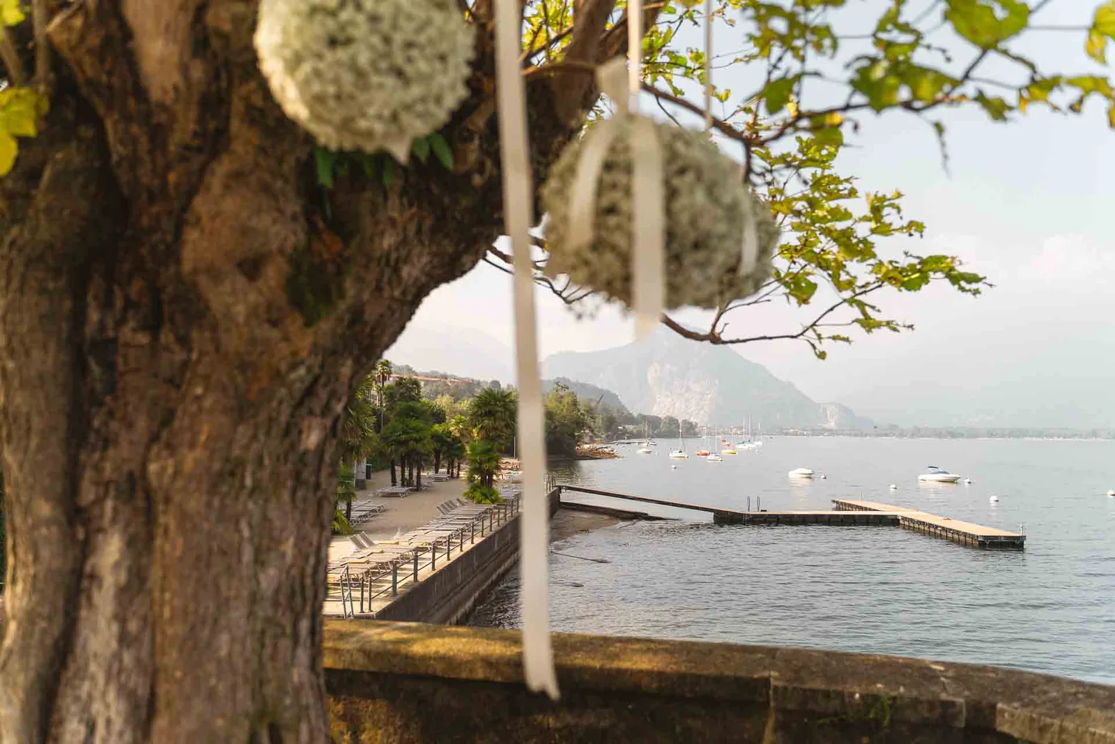 Una sfera di fiori bianchi appesa al ramo, con il pontile e il lago sullo sfondo