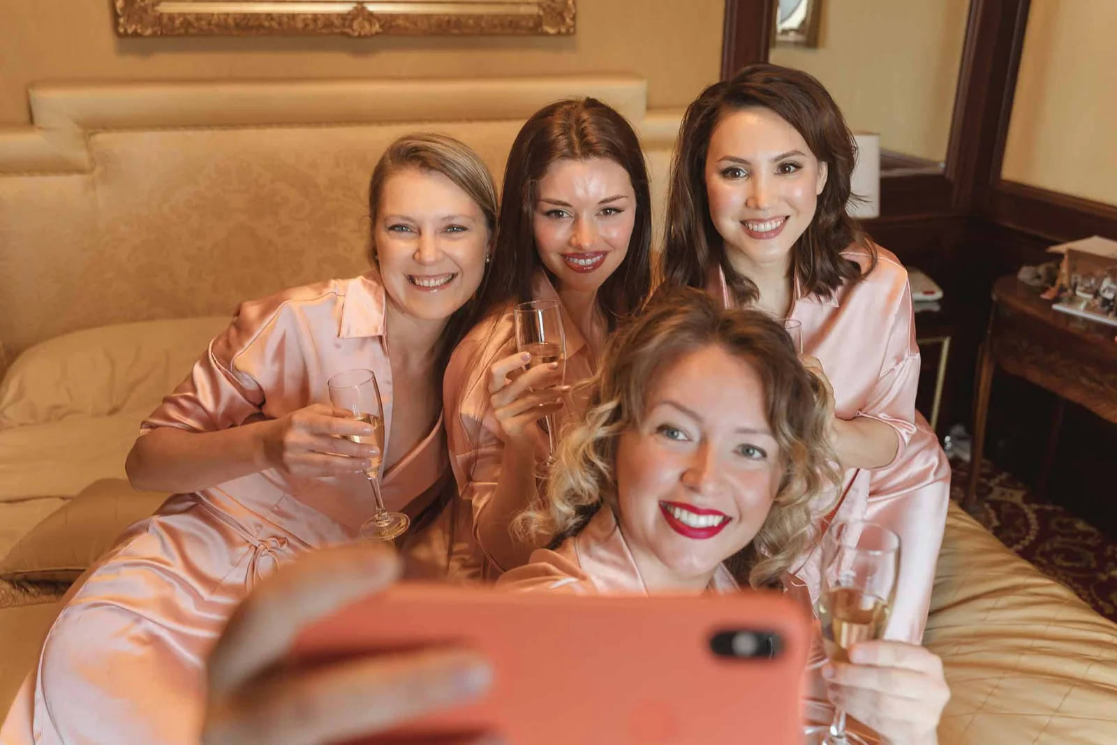 Un selfie delle amiche sul letto, tra risate e calici
