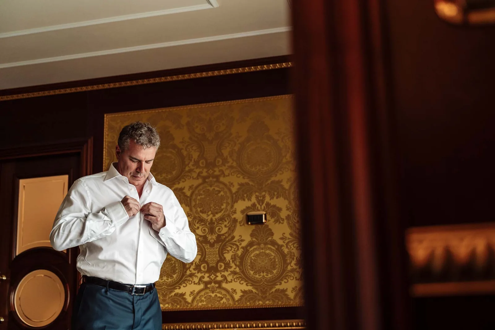 Lo sposo si abbottona la camicia nella sua camera