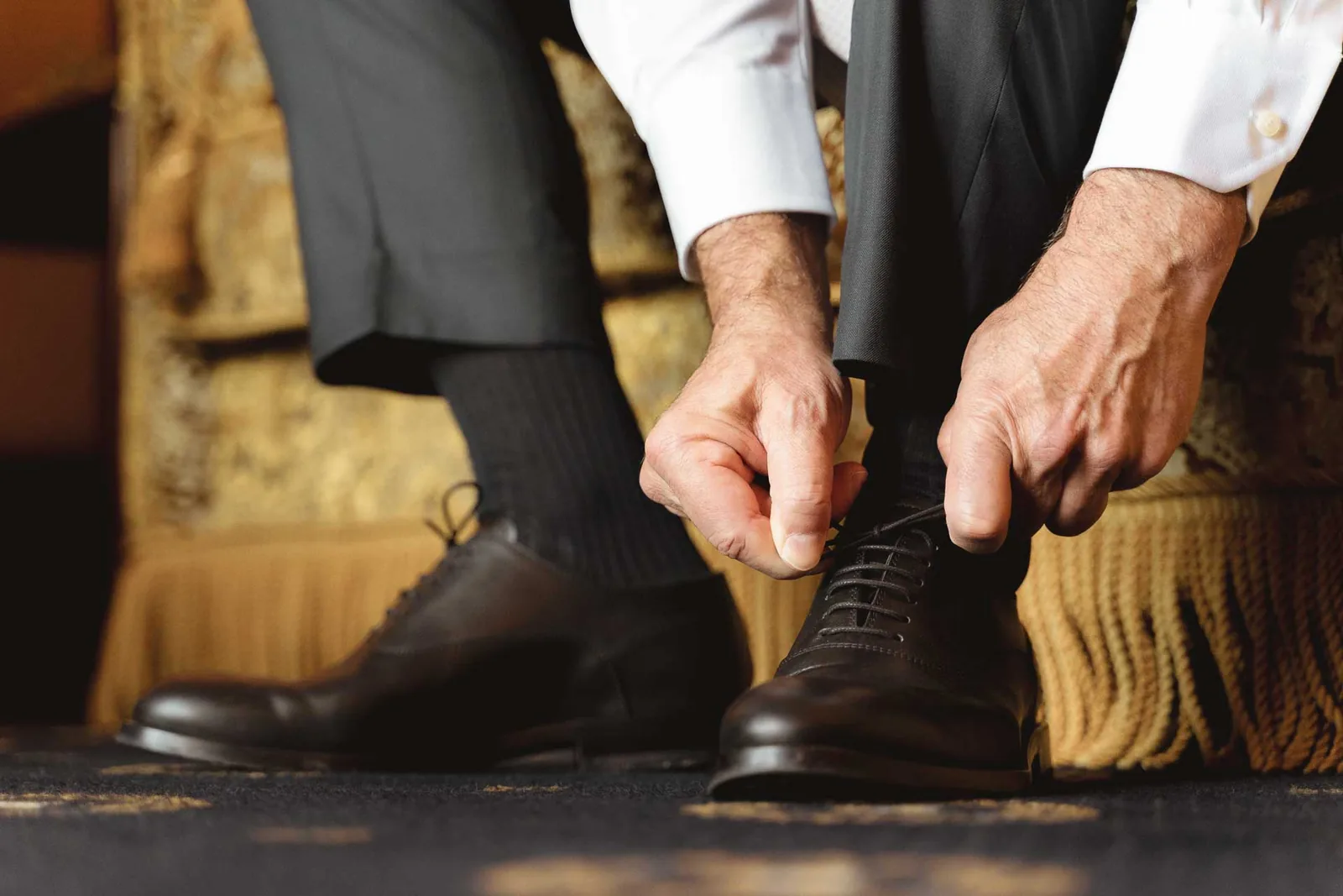 Lo sposo si allaccia le scarpe, sul tappeto della camera