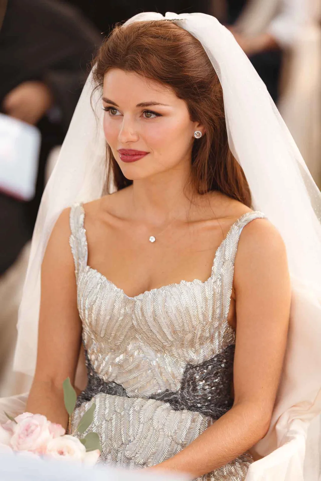 La sposa seduta alla cerimonia, con il velo e un leggero sorriso