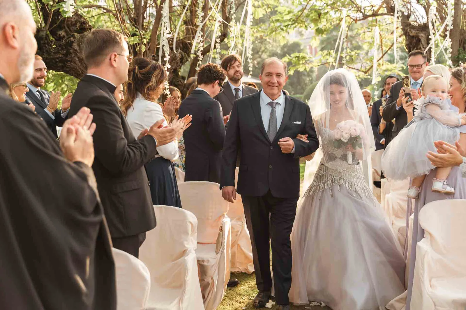 La sposa arriva tra gli invitati in piedi che applaudono