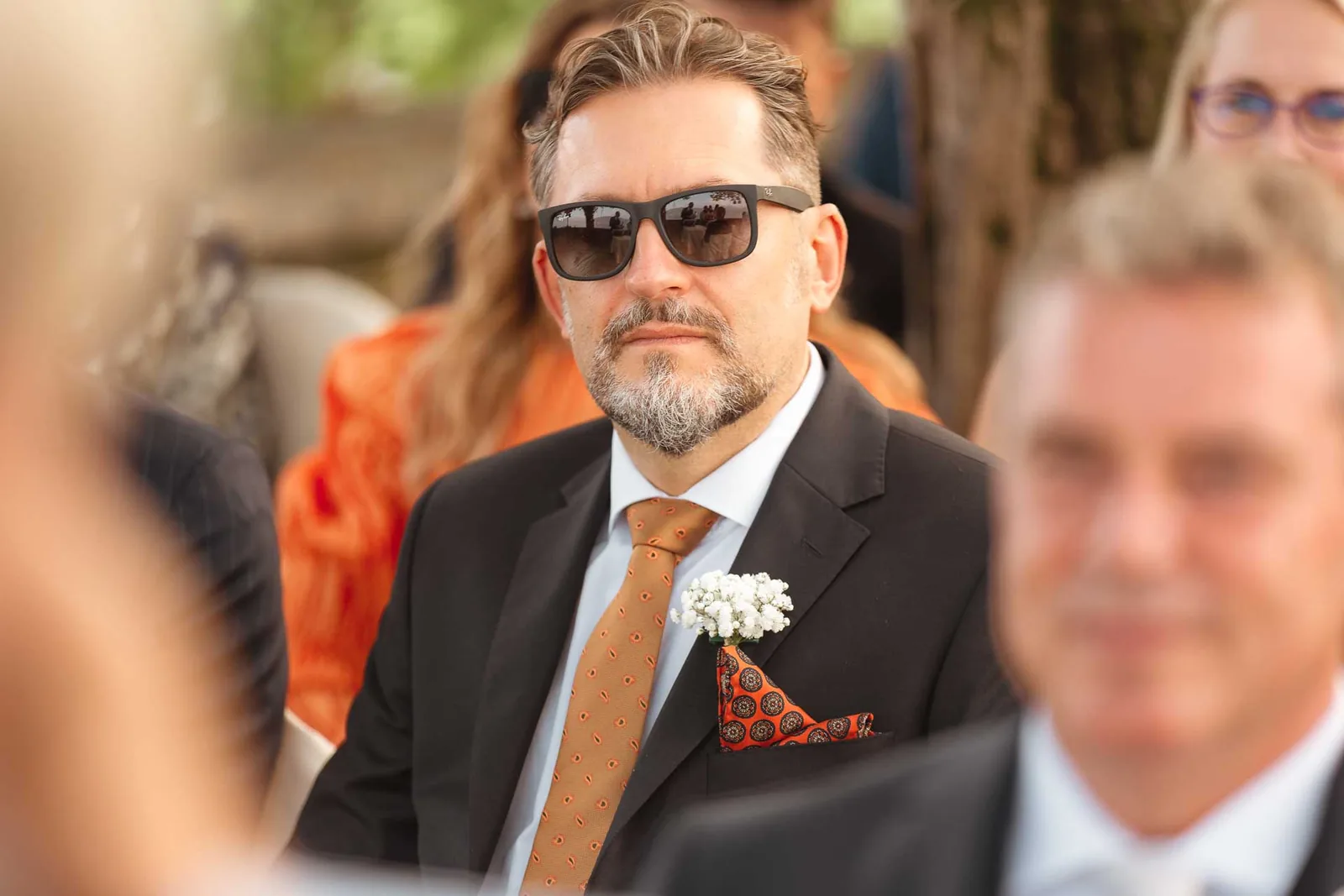 Un invitato con gli occhiali da sole segue la cerimonia
