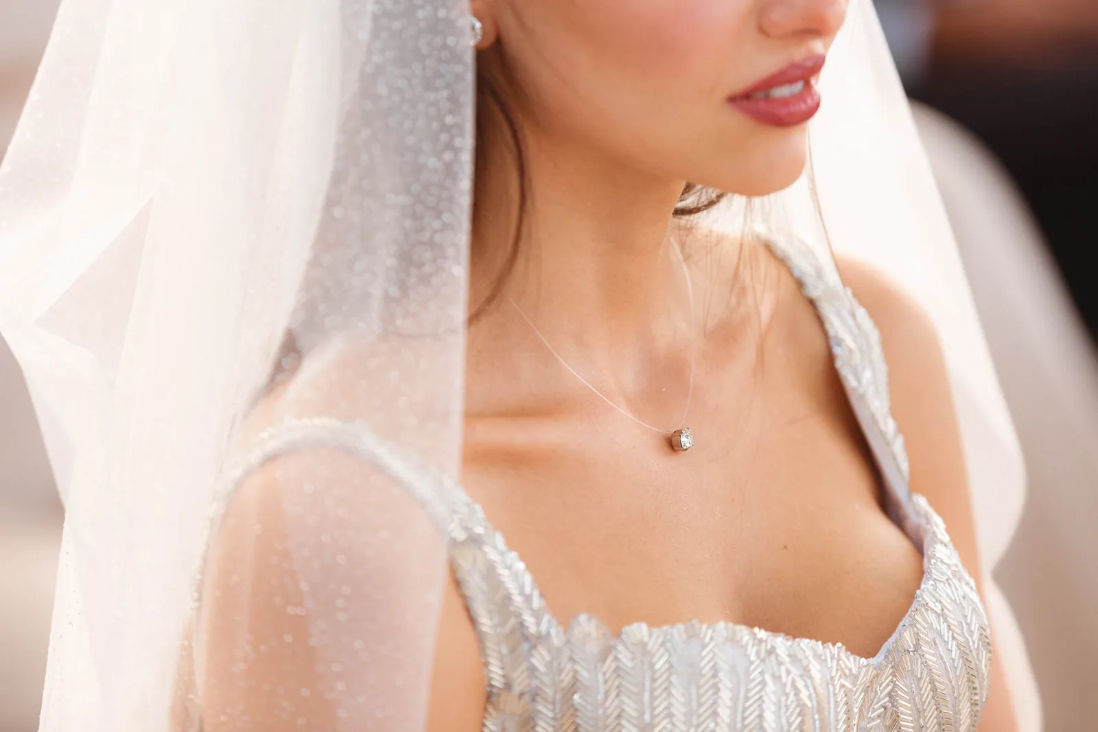 Il velo e il ricamo dell'abito della sposa, in primo piano