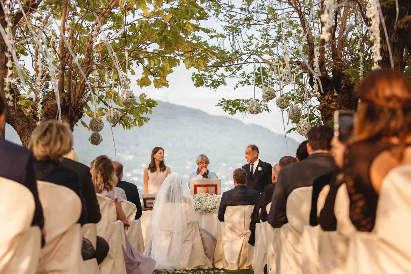 Gli sposi davanti al tavolo della cerimonia, tra gli invitati e il Lago Maggiore