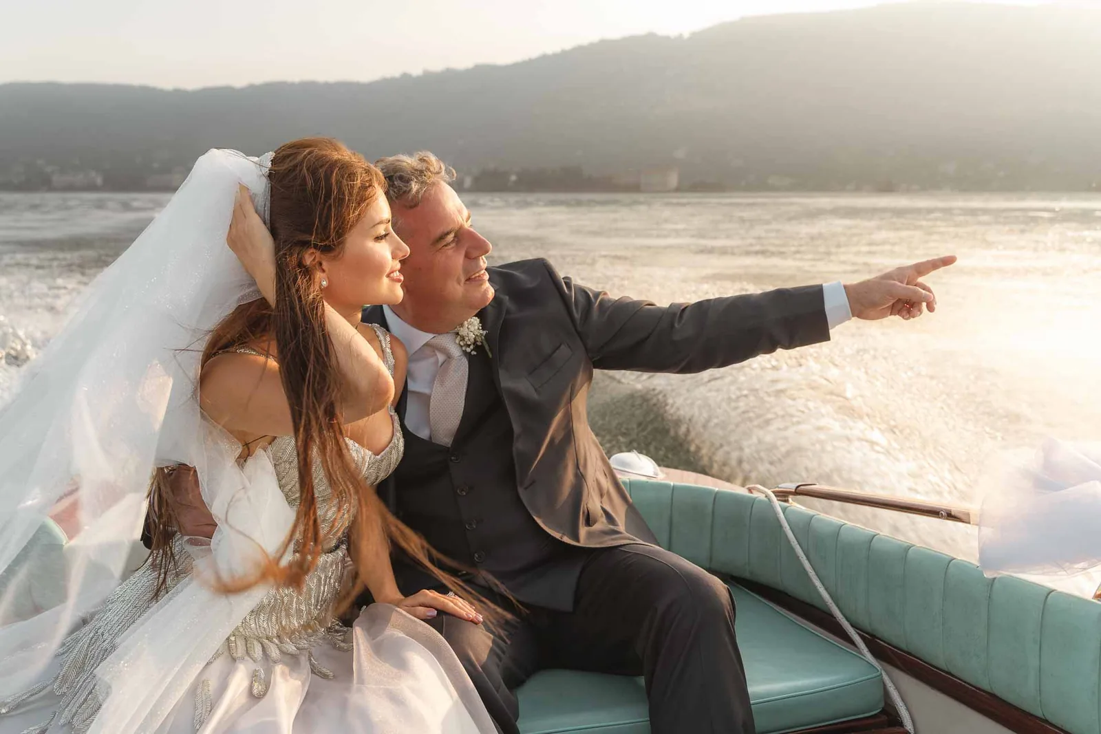 Sul motoscafo, lo sposo indica qualcosa sul lago alla sposa