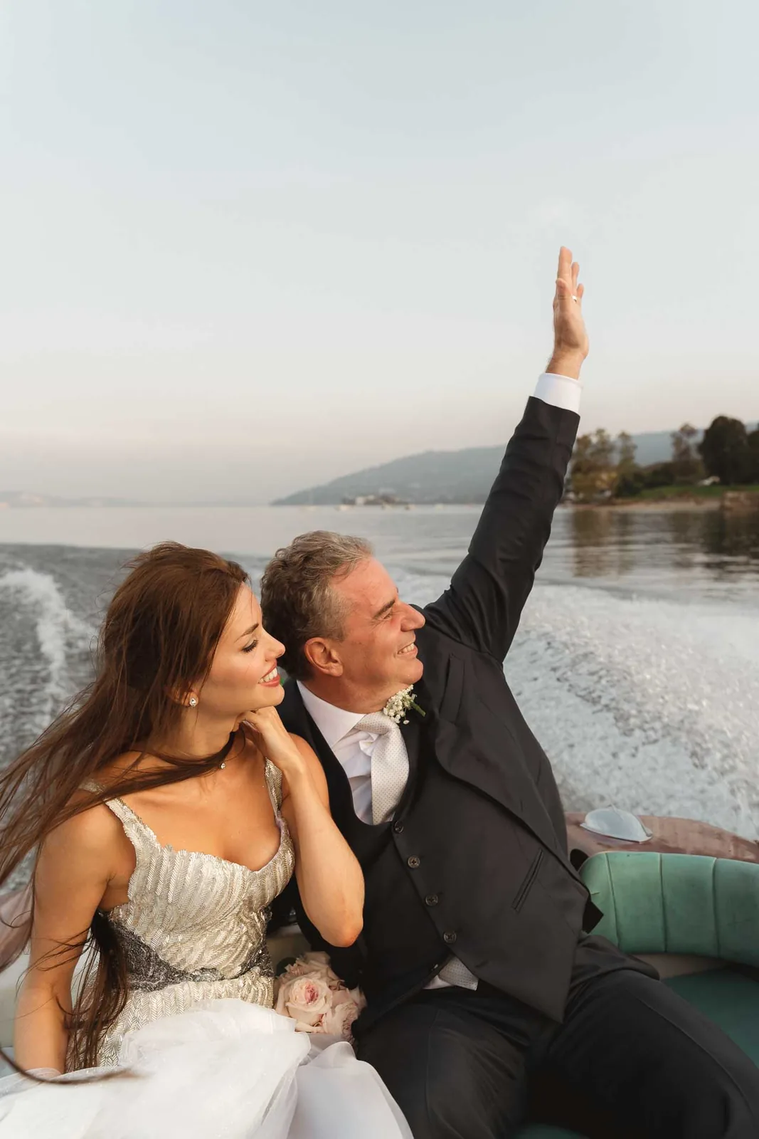 Lo sposo saluta con il braccio alzato, sul motoscafo accanto alla sposa
