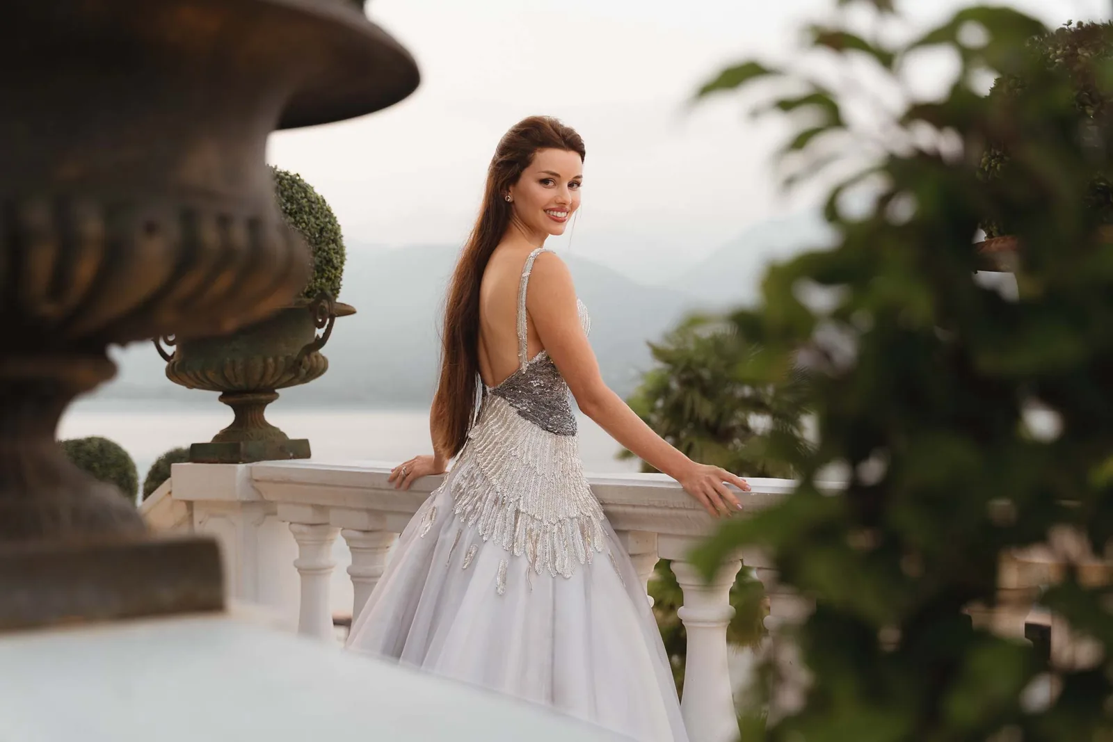 La sposa sorride sulla terrazza, con le montagne sullo sfondo