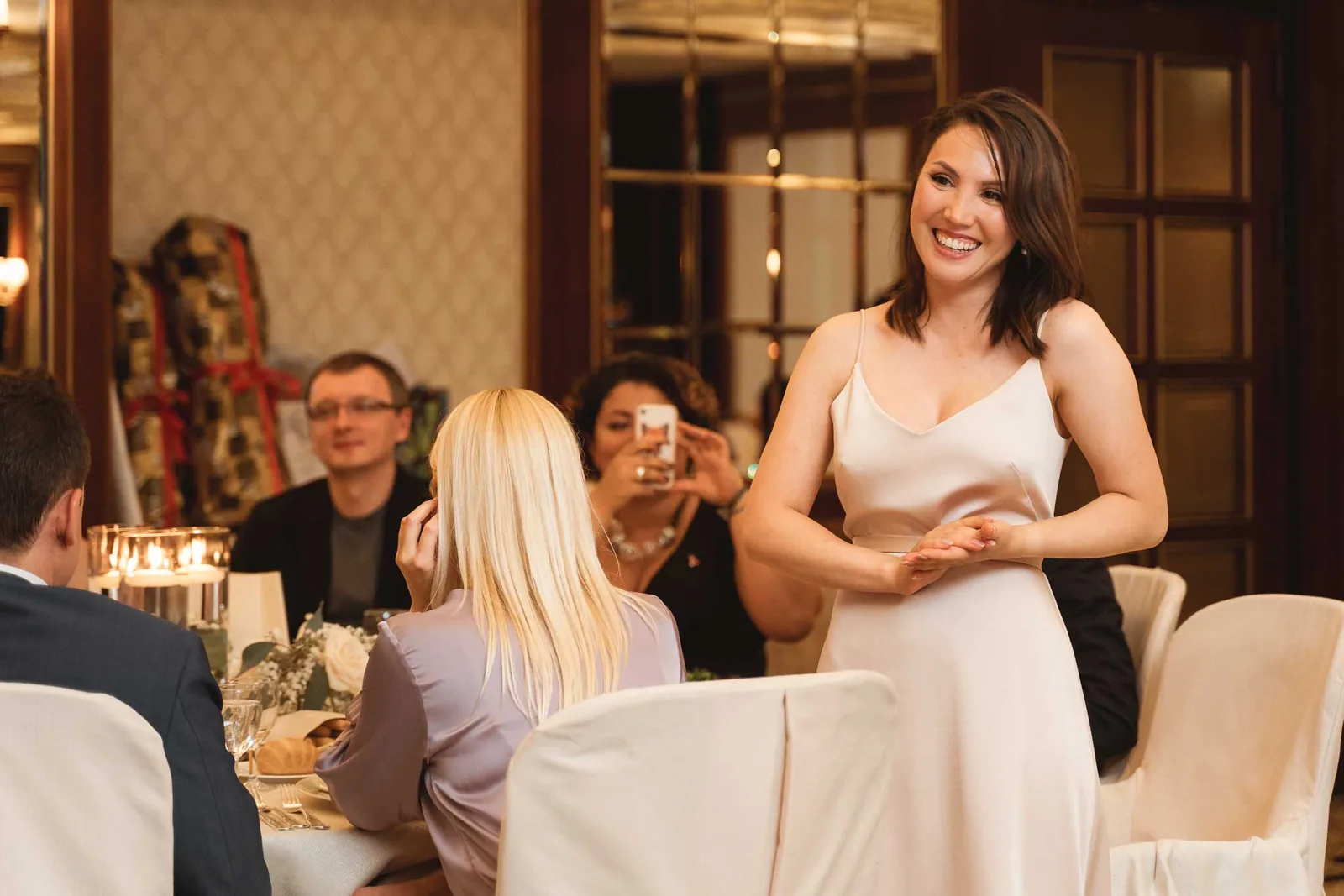 La sposa sorride in piedi accanto a un tavolo di invitati