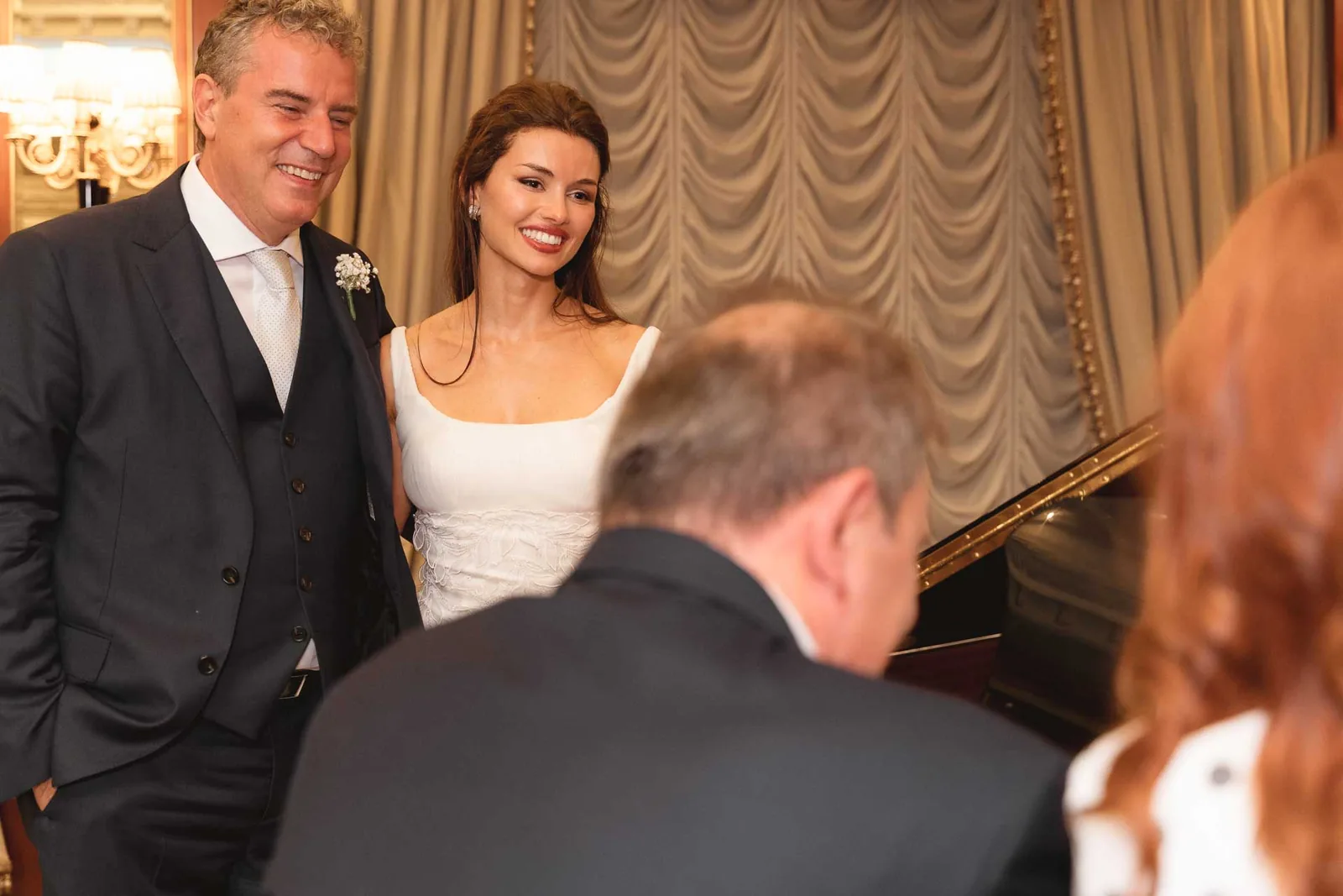 Gli sposi in piedi accanto al pianoforte, sorridenti