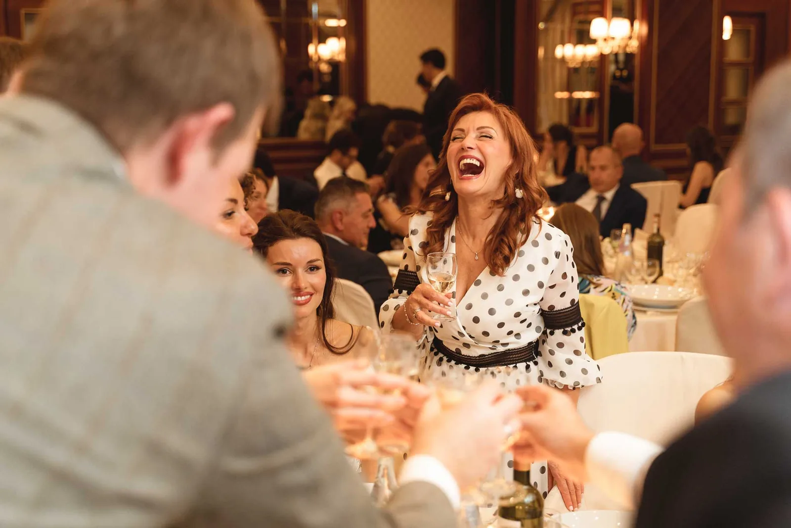 Una donna ride a tavola tra gli invitati