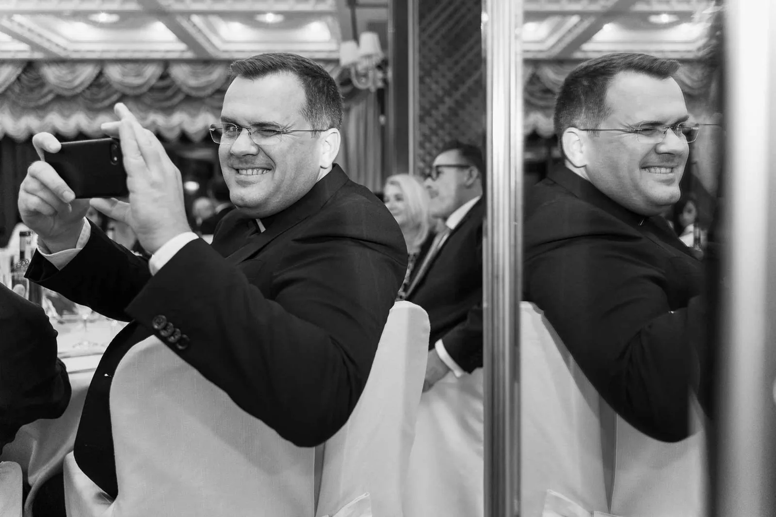 In bianco e nero, un invitato fotografa con il telefono