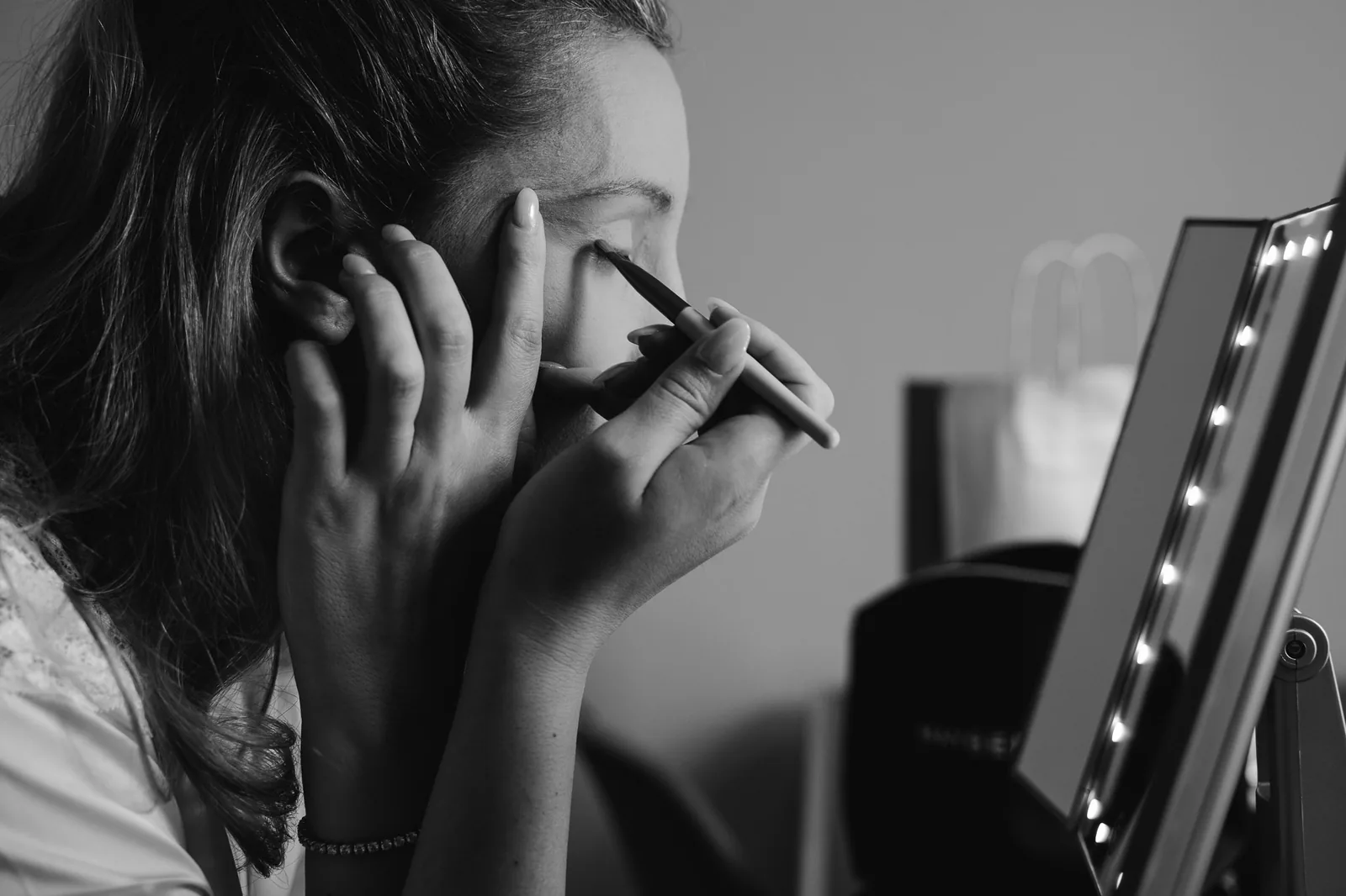 In bianco e nero, il trucco davanti allo specchio illuminato durante i preparativi