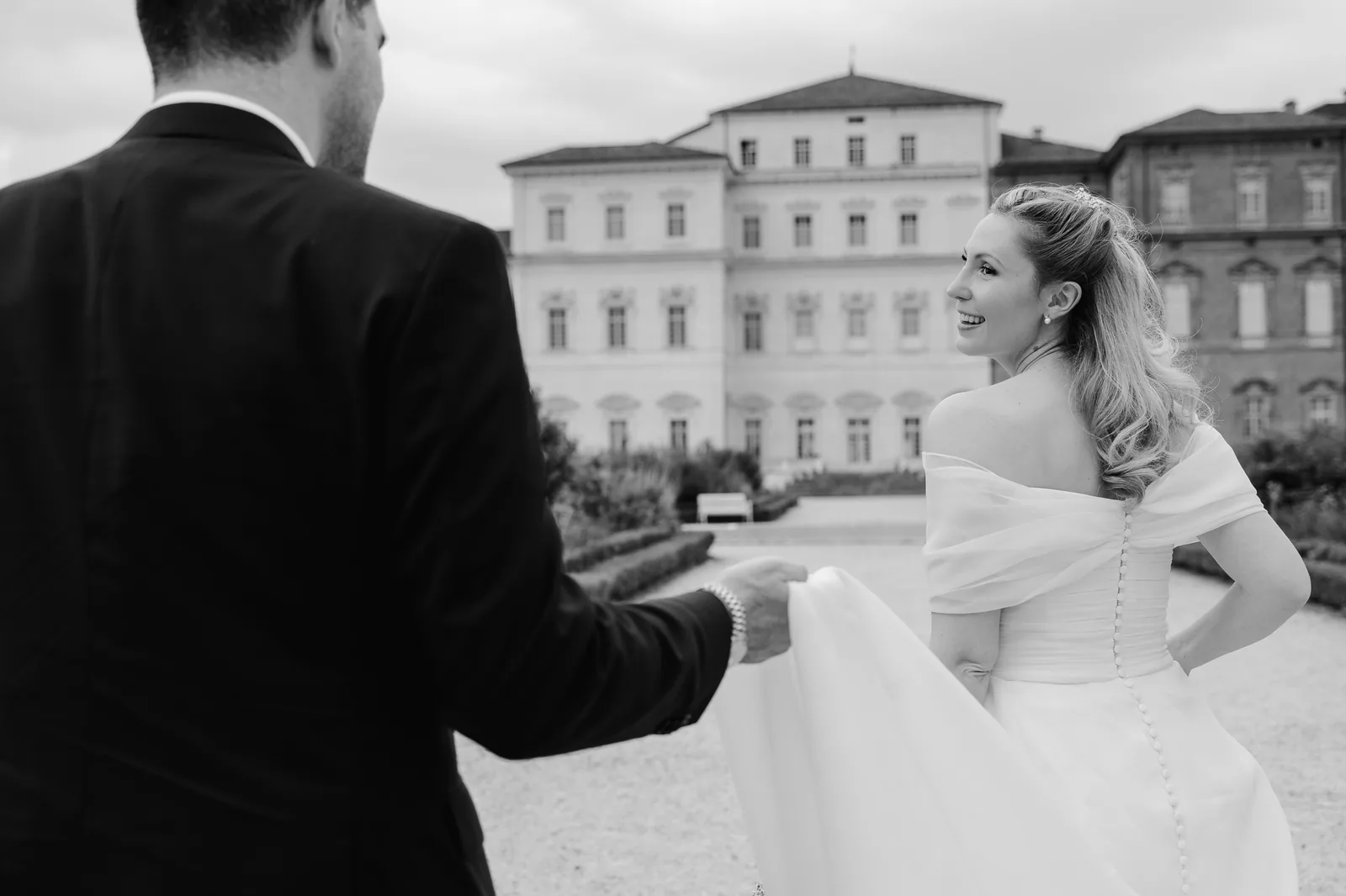 In bianco e nero, lo sposo tiene lo strascico della sposa nei giardini della Reggia di Venaria