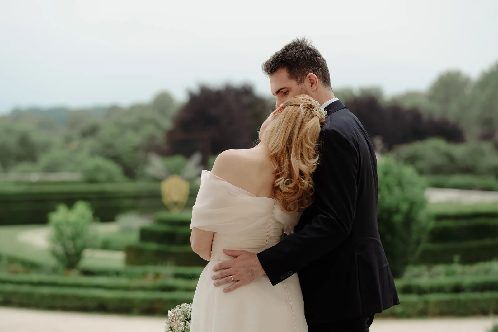 Lo sposo bacia la testa della sposa davanti alle siepi dei giardini della Reggia di Venaria