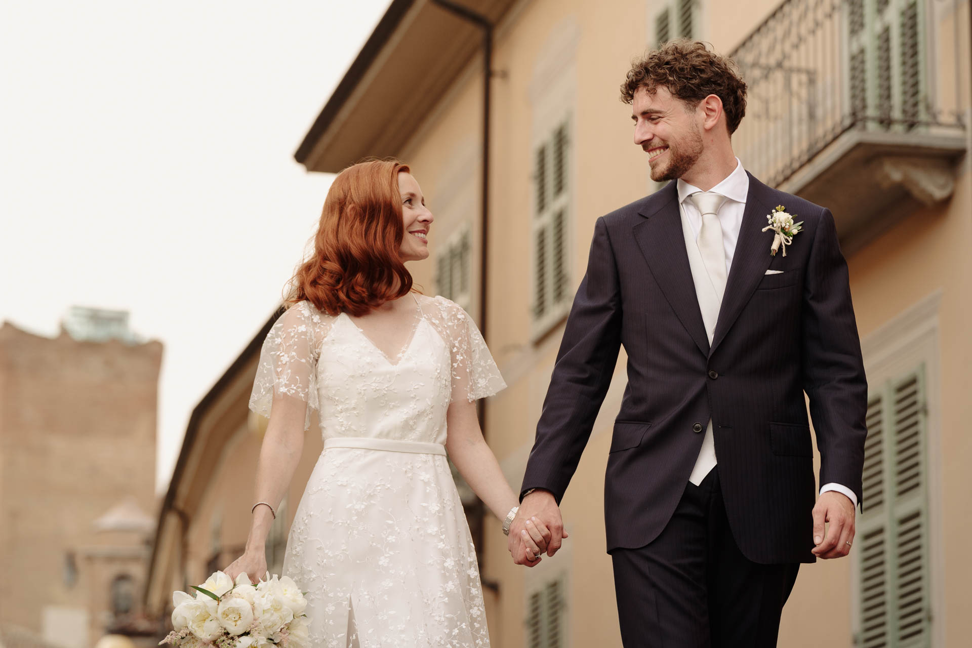 Gli sposi camminano mano nella mano e si sorridono, tra le case di Barbaresco