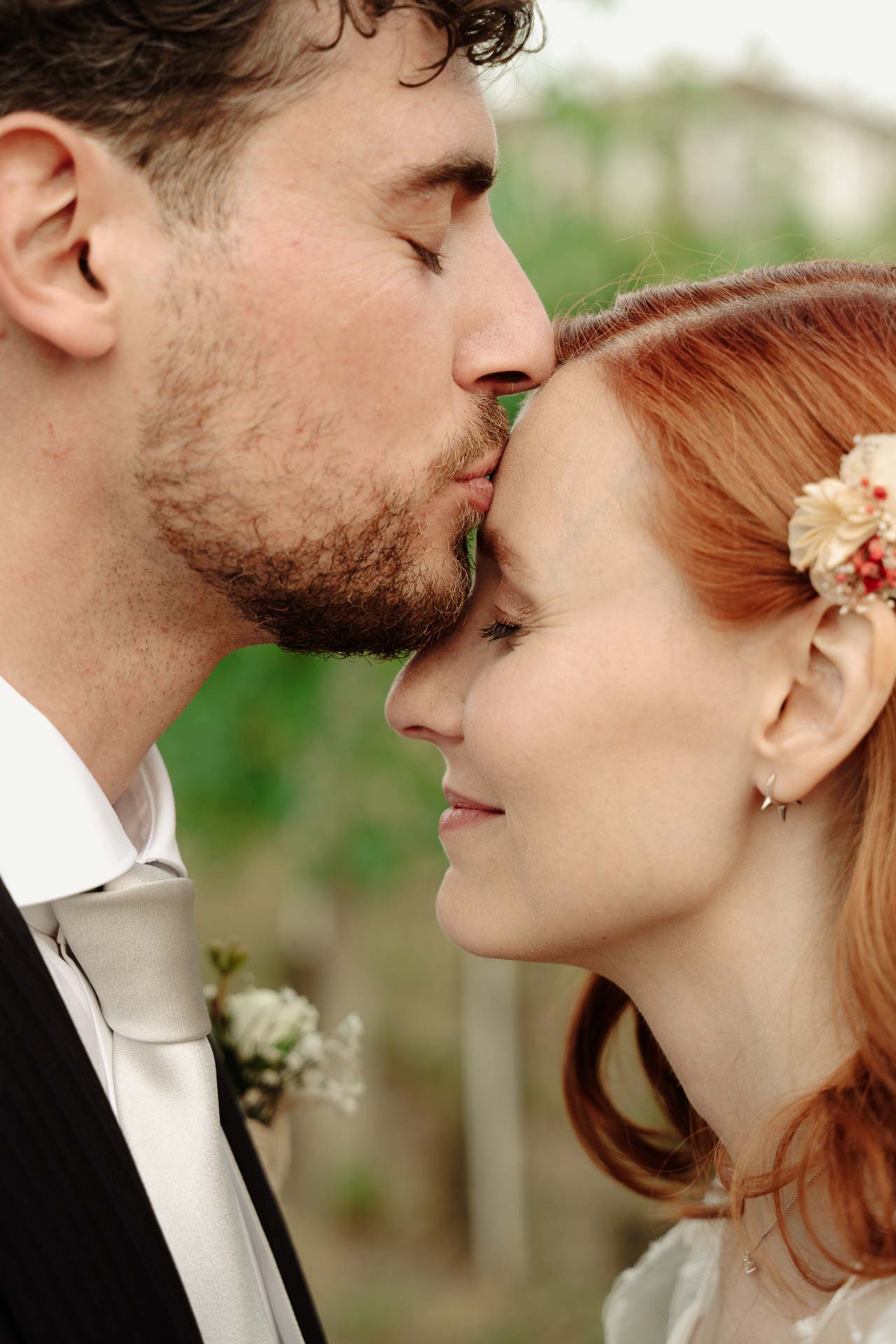 Lo sposo bacia la fronte della sposa, che sorride a occhi chiusi