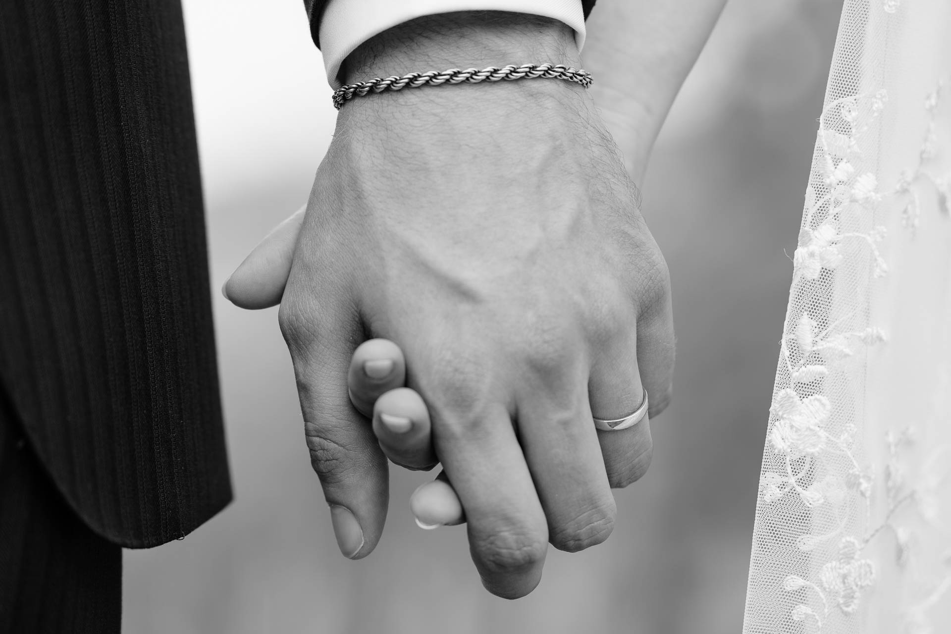 In bianco e nero, le mani intrecciate degli sposi
