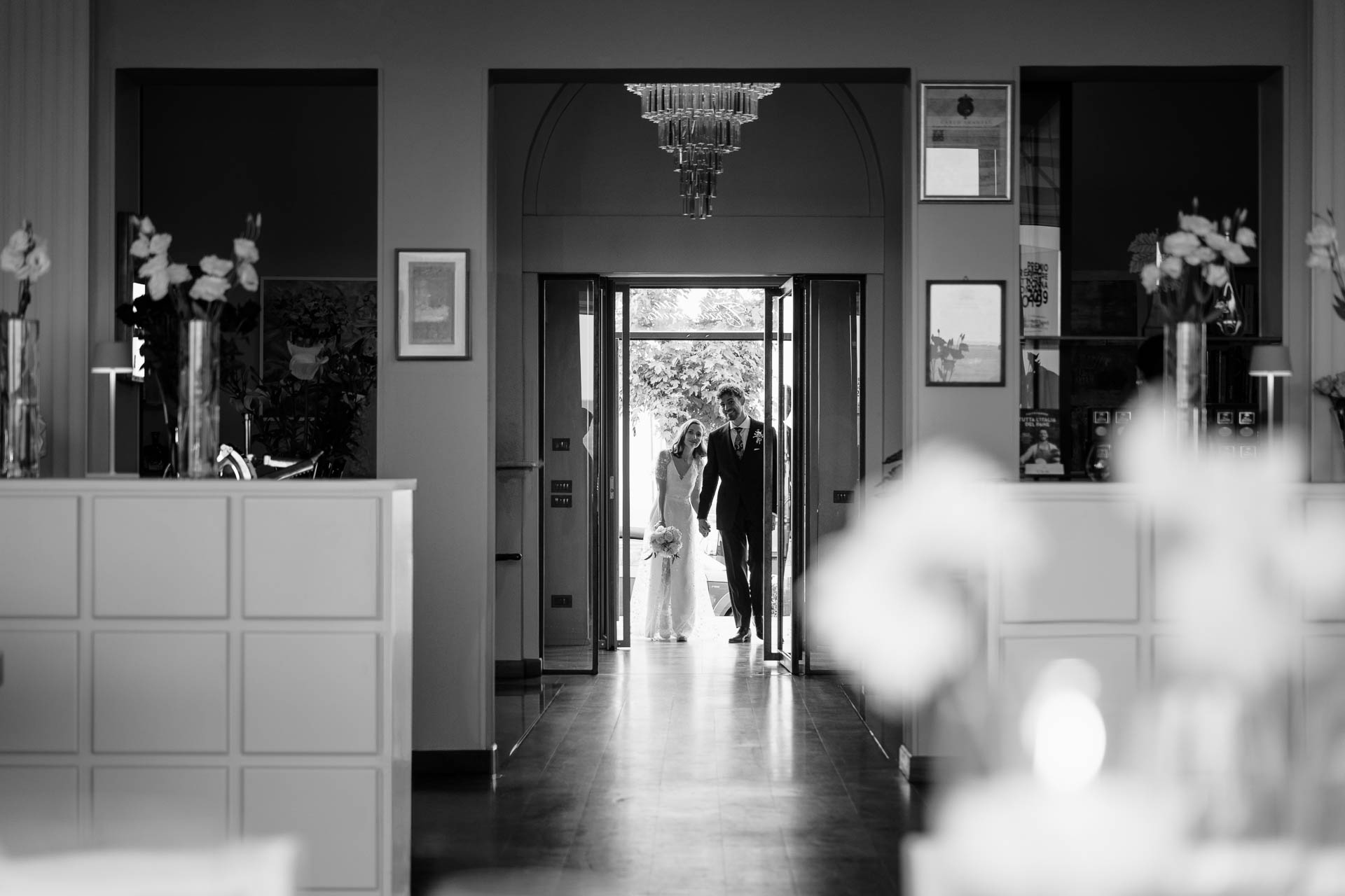 In bianco e nero, gli sposi entrano nella sala, in fondo al corridoio