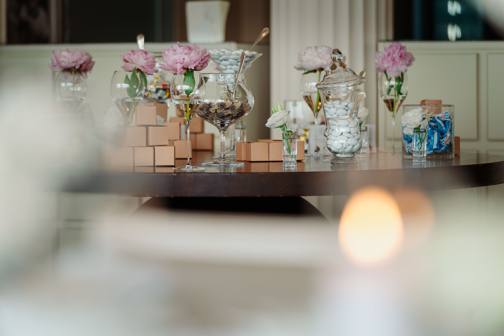 Il tavolo della confettata con le peonie, oltre la luce di una candela