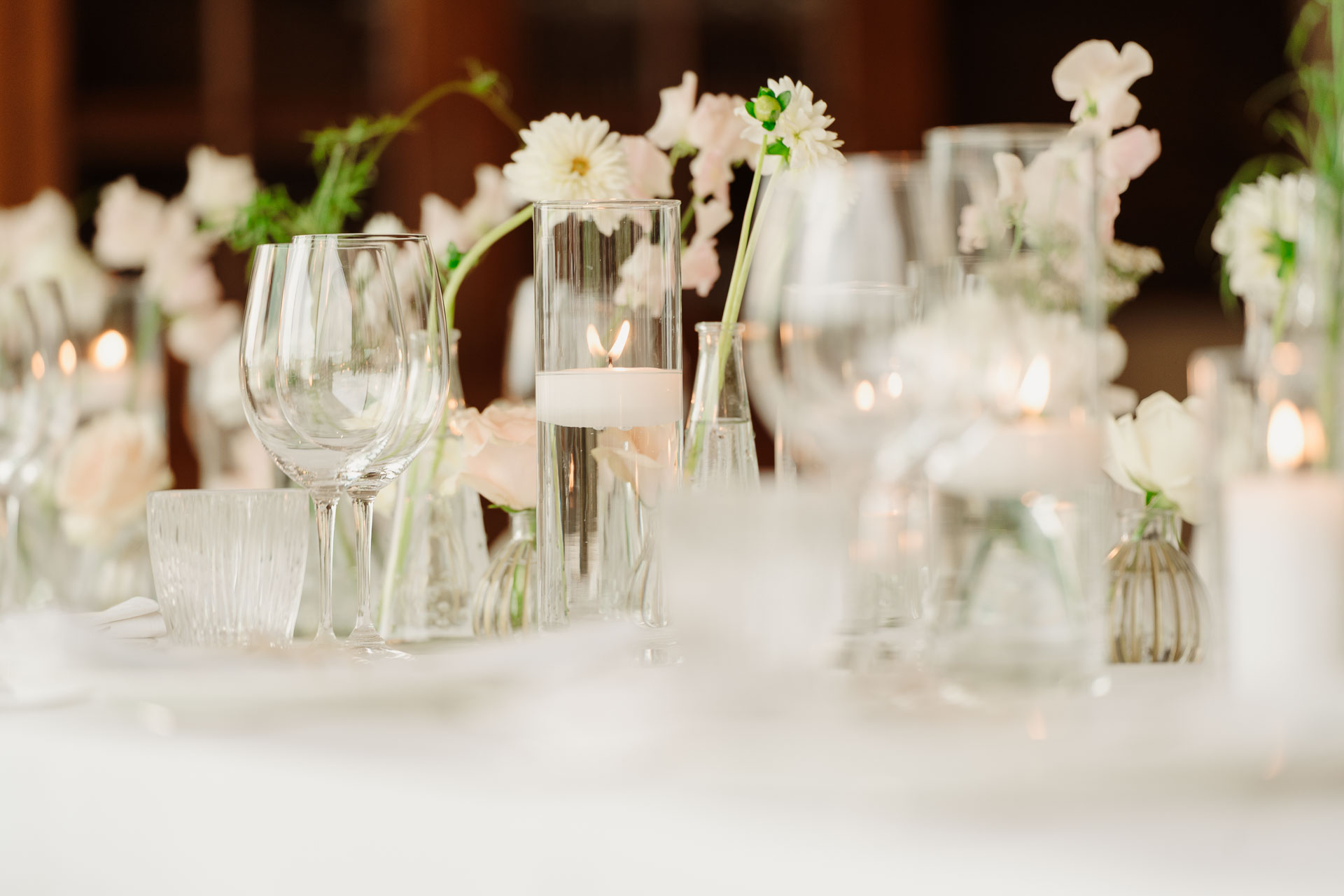 I bicchieri e i fiori bianchi sulla tavola, nella luce delle candele