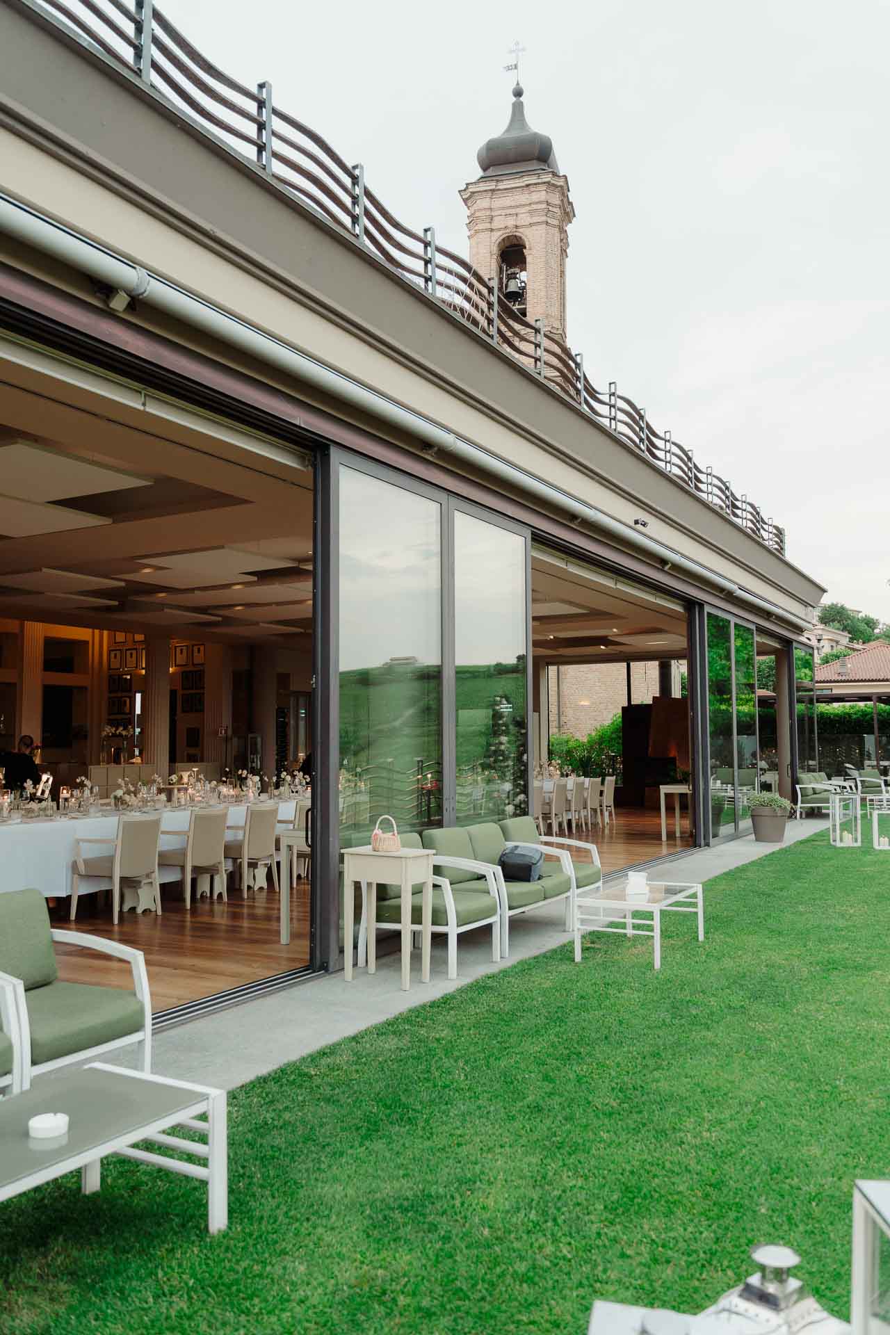 La sala vetrata della Ciau del Tornavento affacciata sul prato, con il campanile in fondo