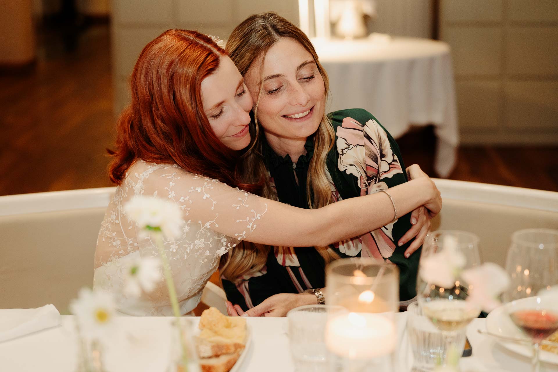 La sposa abbraccia un'amica a tavola