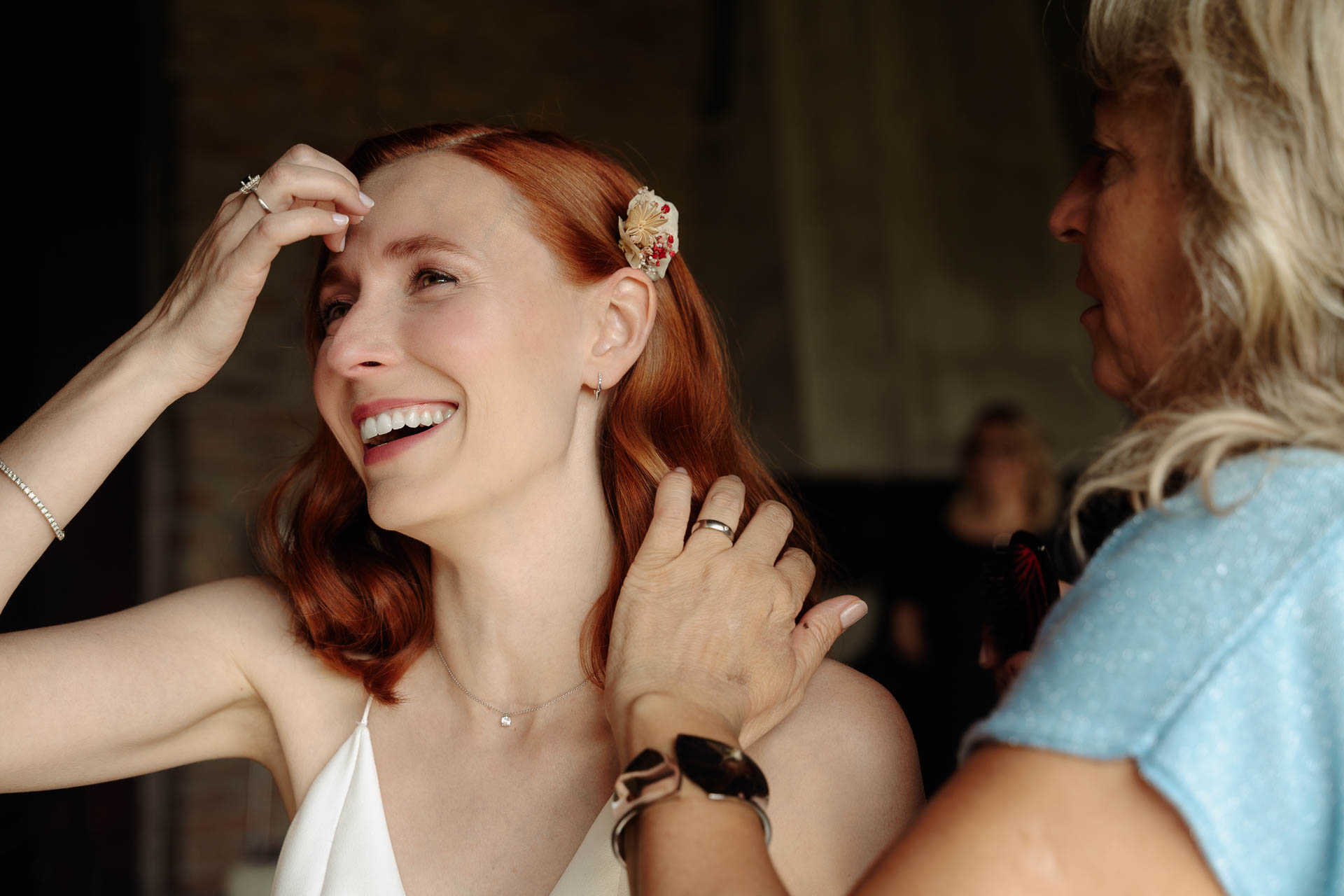 La sposa ride e si sistema i capelli, accanto alla parrucchiera