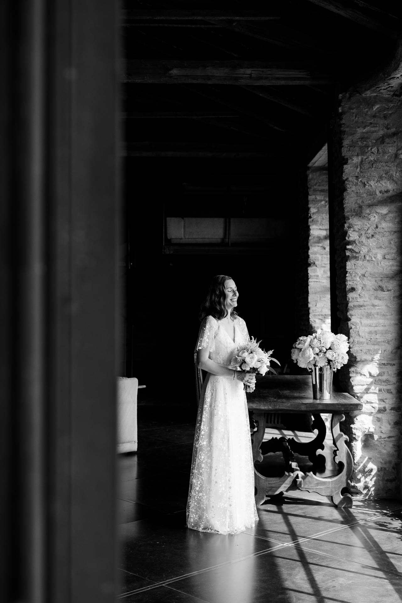 In bianco e nero, la sposa con il bouquet nella sala, nella luce della finestra