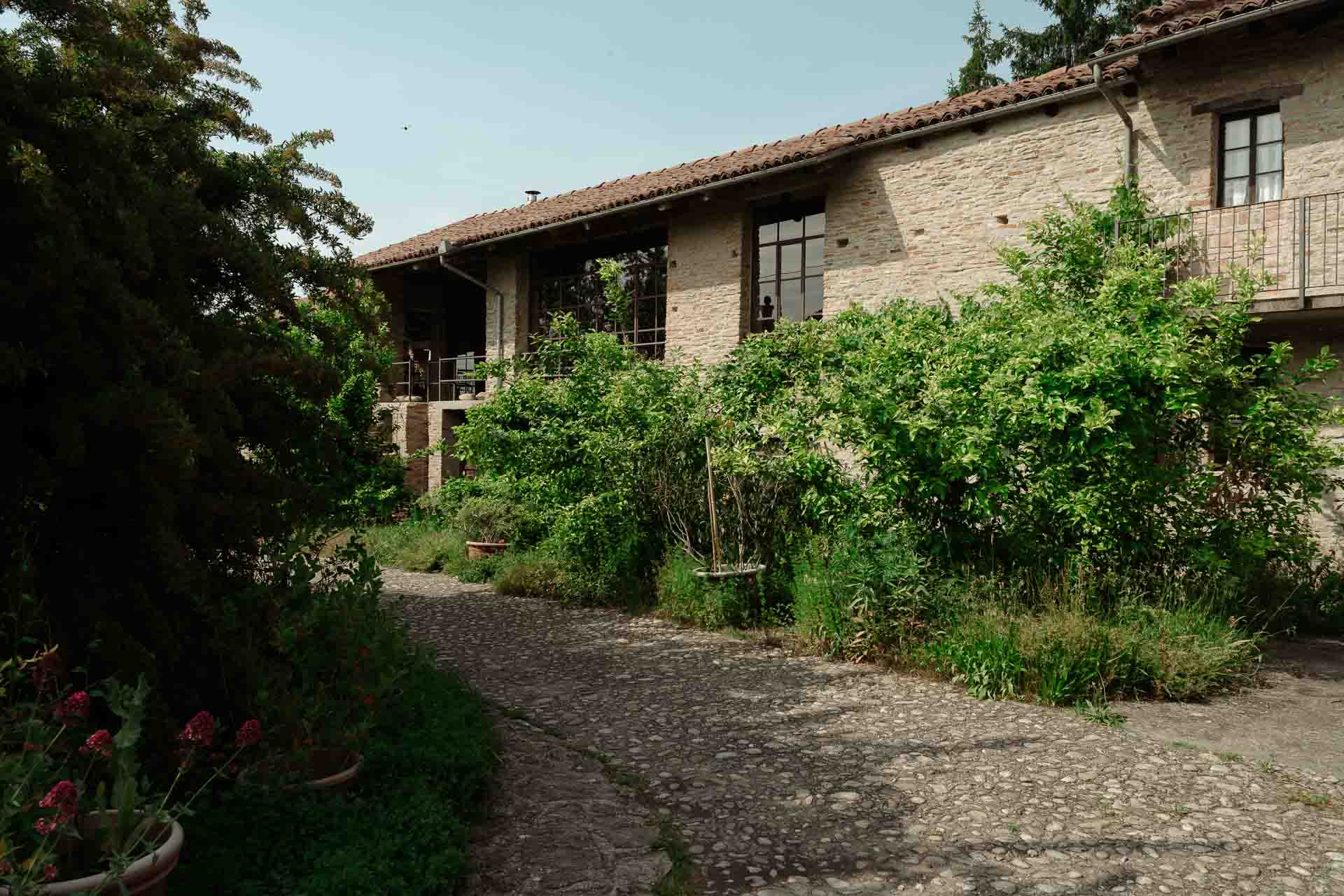 Il vialetto di ciottoli e la cascina di mattoni, tra il verde