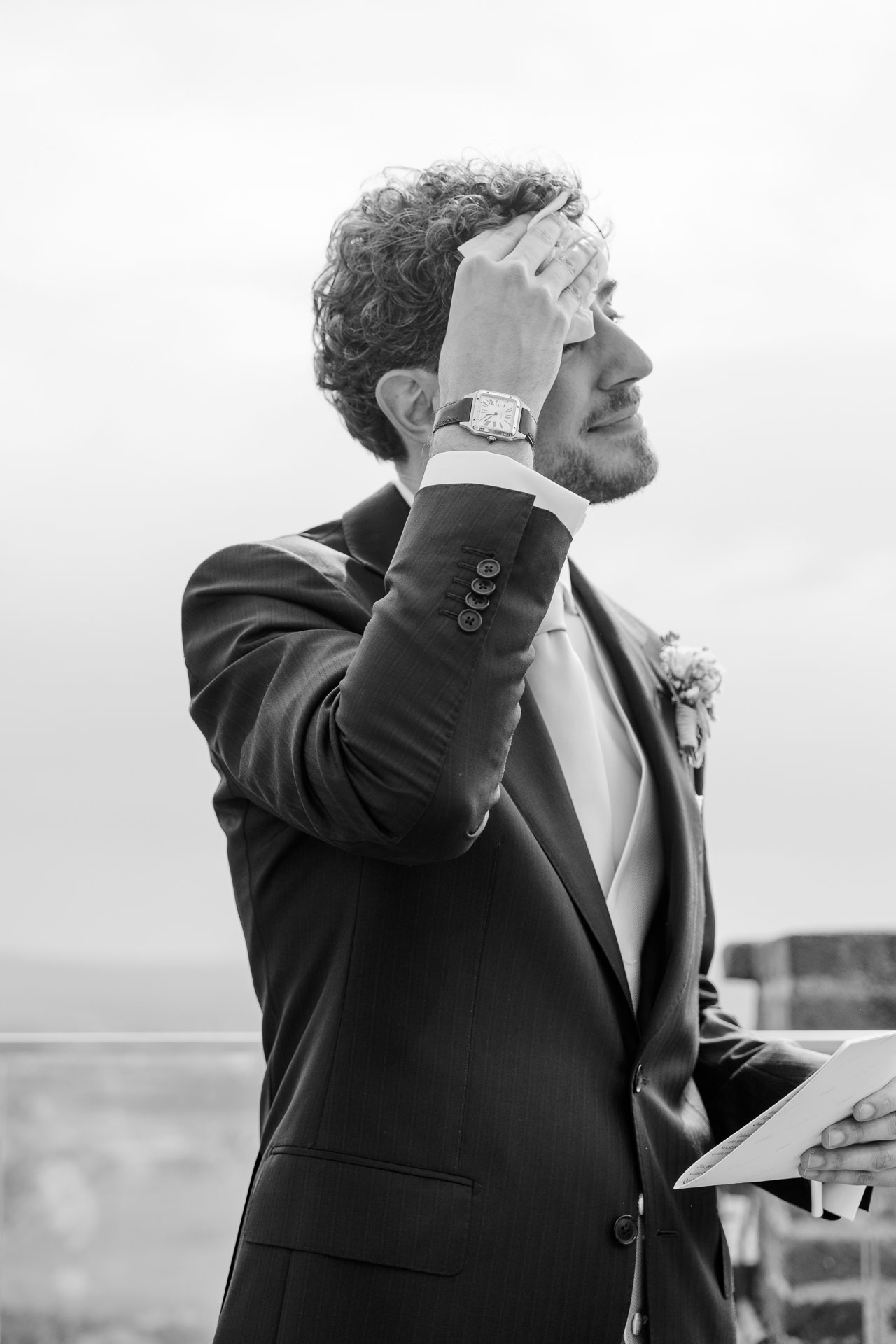 In bianco e nero, lo sposo si porta la mano alla fronte, emozionato, sulla terrazza della torre