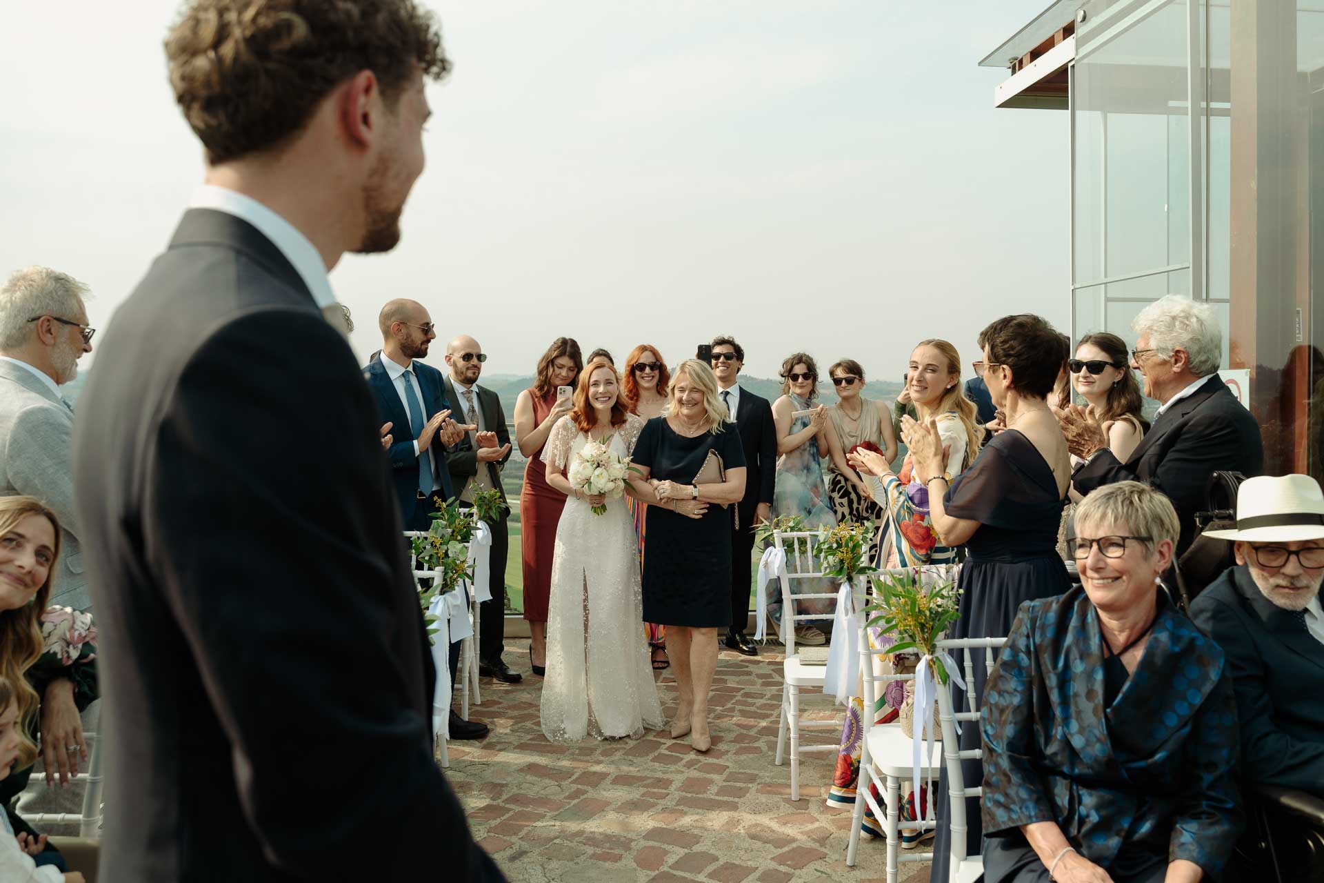 Lo sposo guarda la sposa che arriva tra gli invitati, sulla terrazza della torre