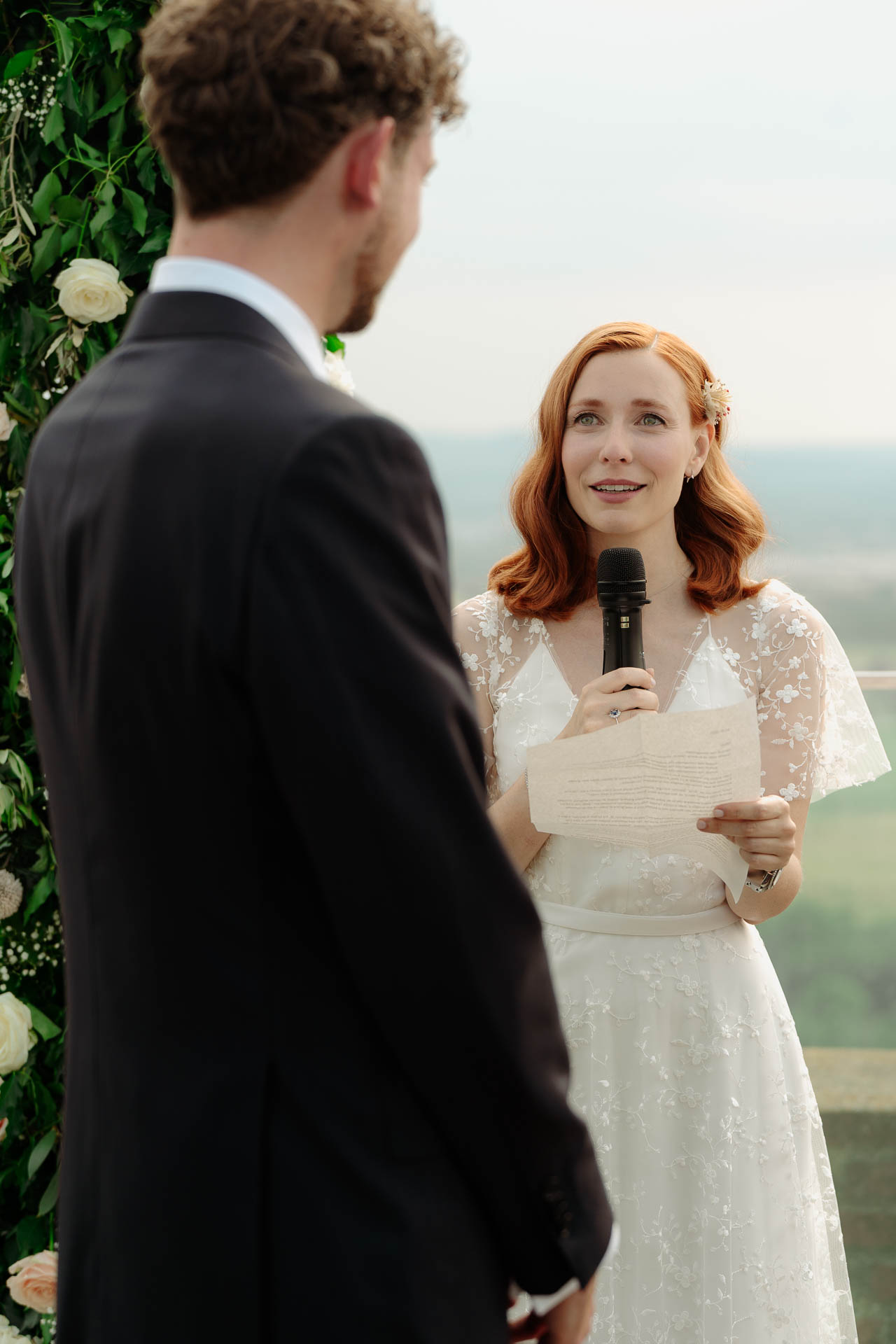 La sposa legge le promesse al microfono, di fronte allo sposo