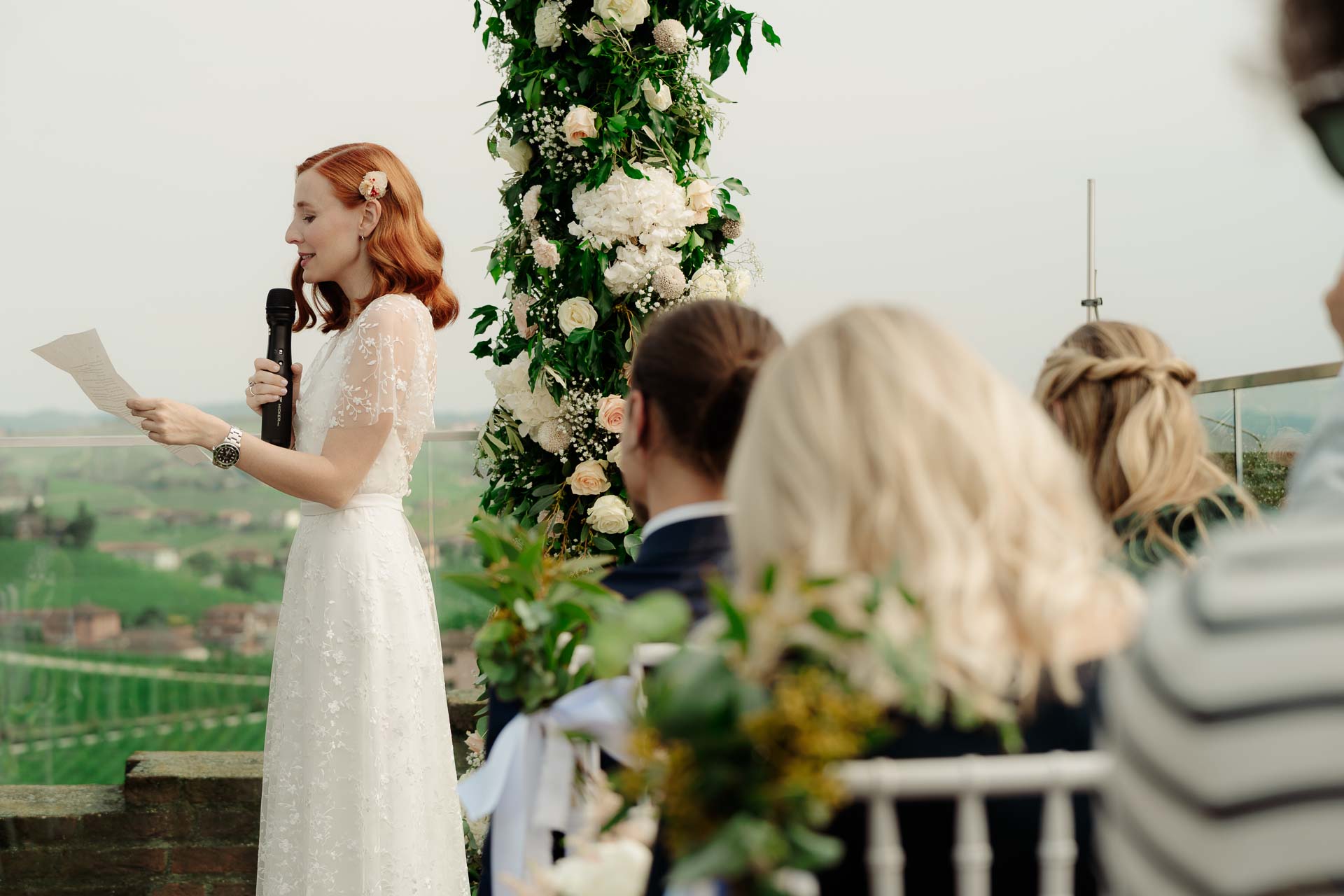 La sposa legge al microfono, vista oltre gli invitati