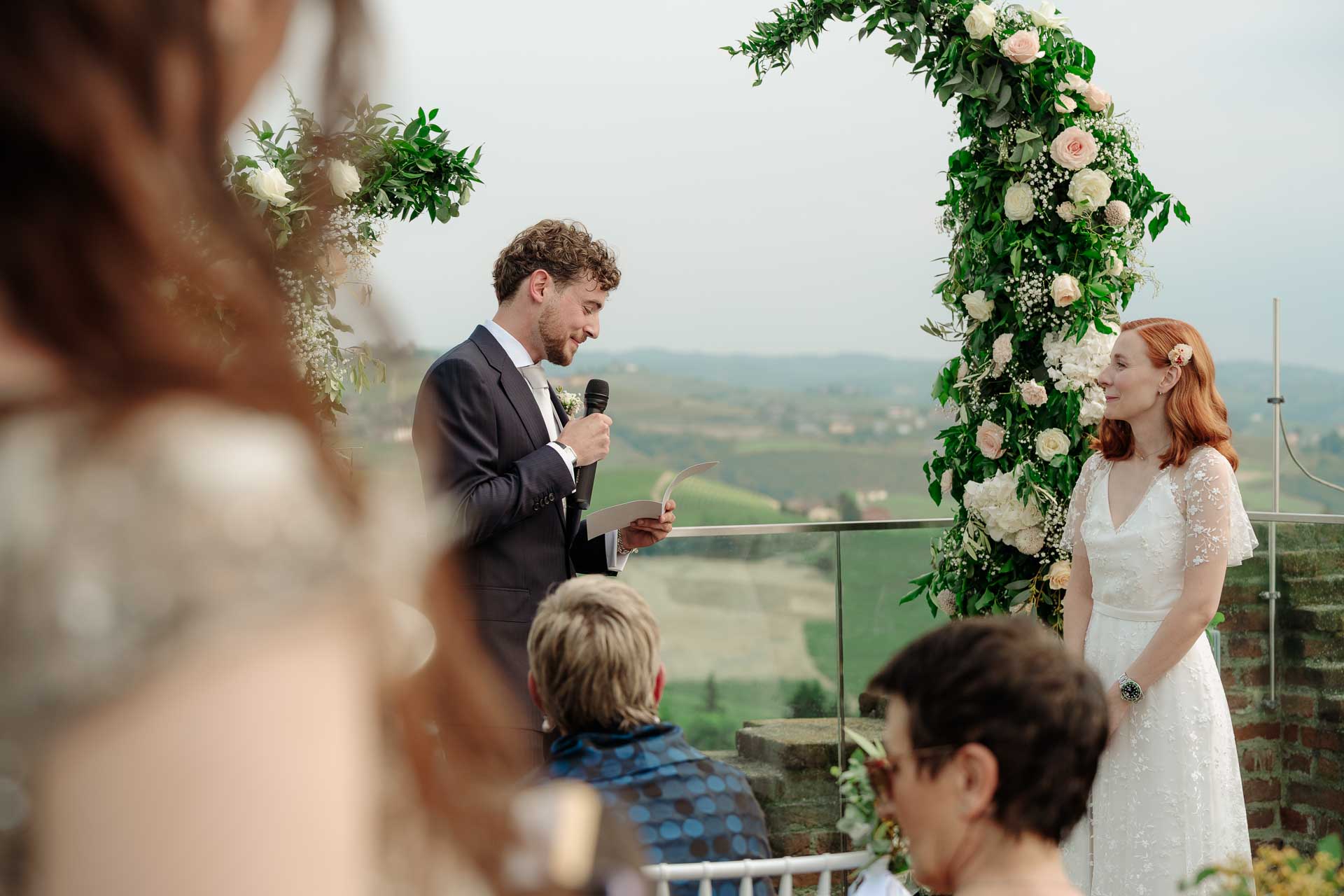 Lo sposo legge le promesse alla sposa, visto oltre gli invitati