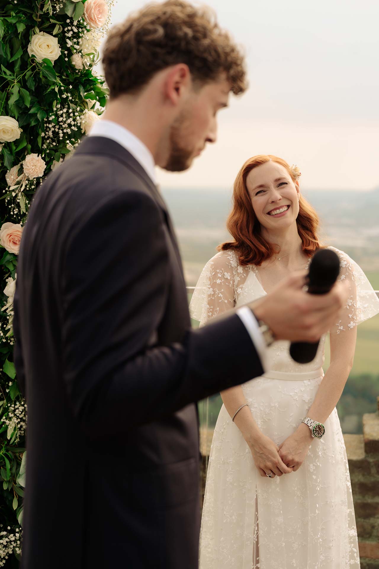 La sposa sorride mentre lo sposo le parla al microfono