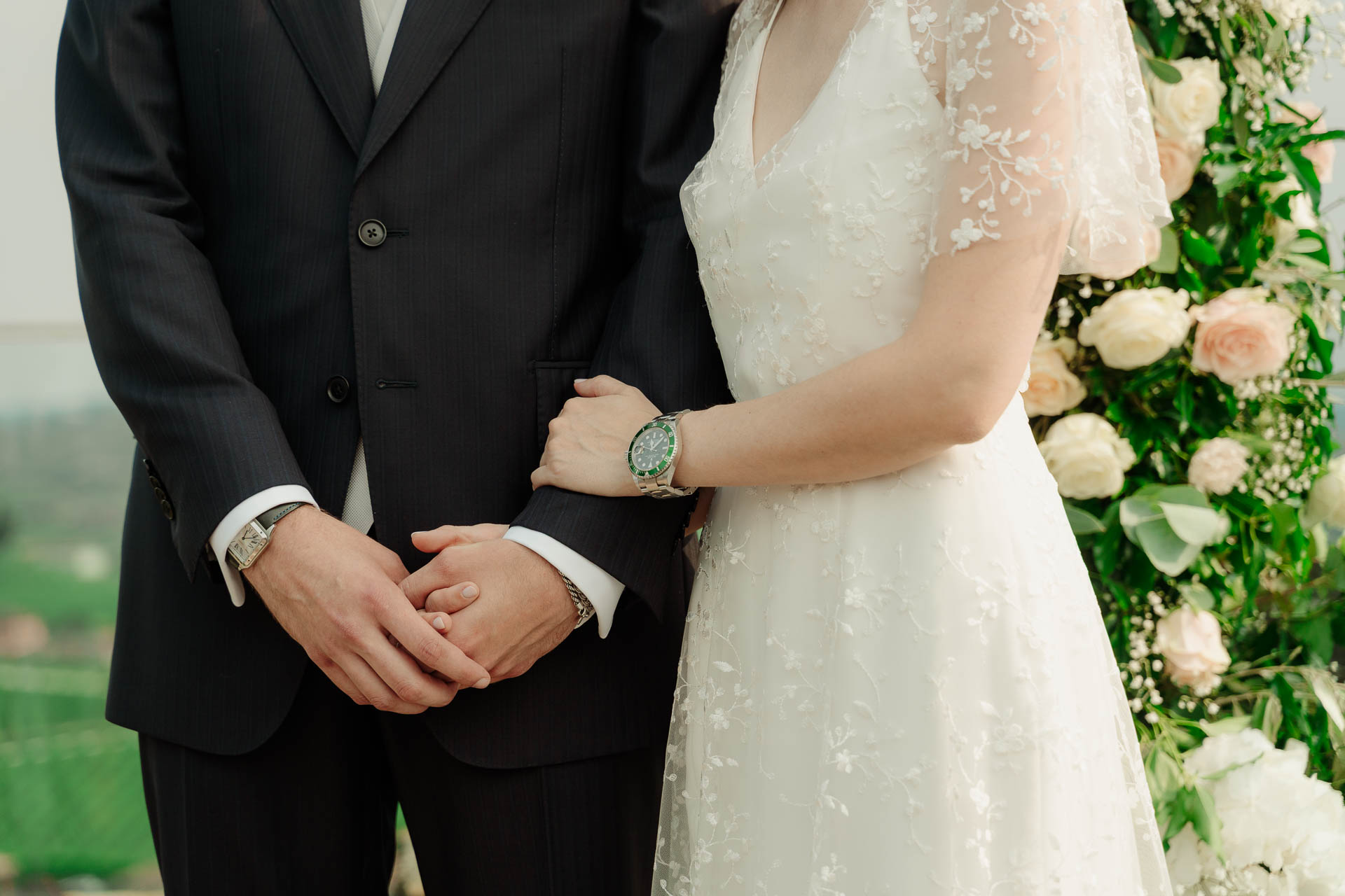 La sposa stringe il braccio dello sposo, accanto all'arco di fiori
