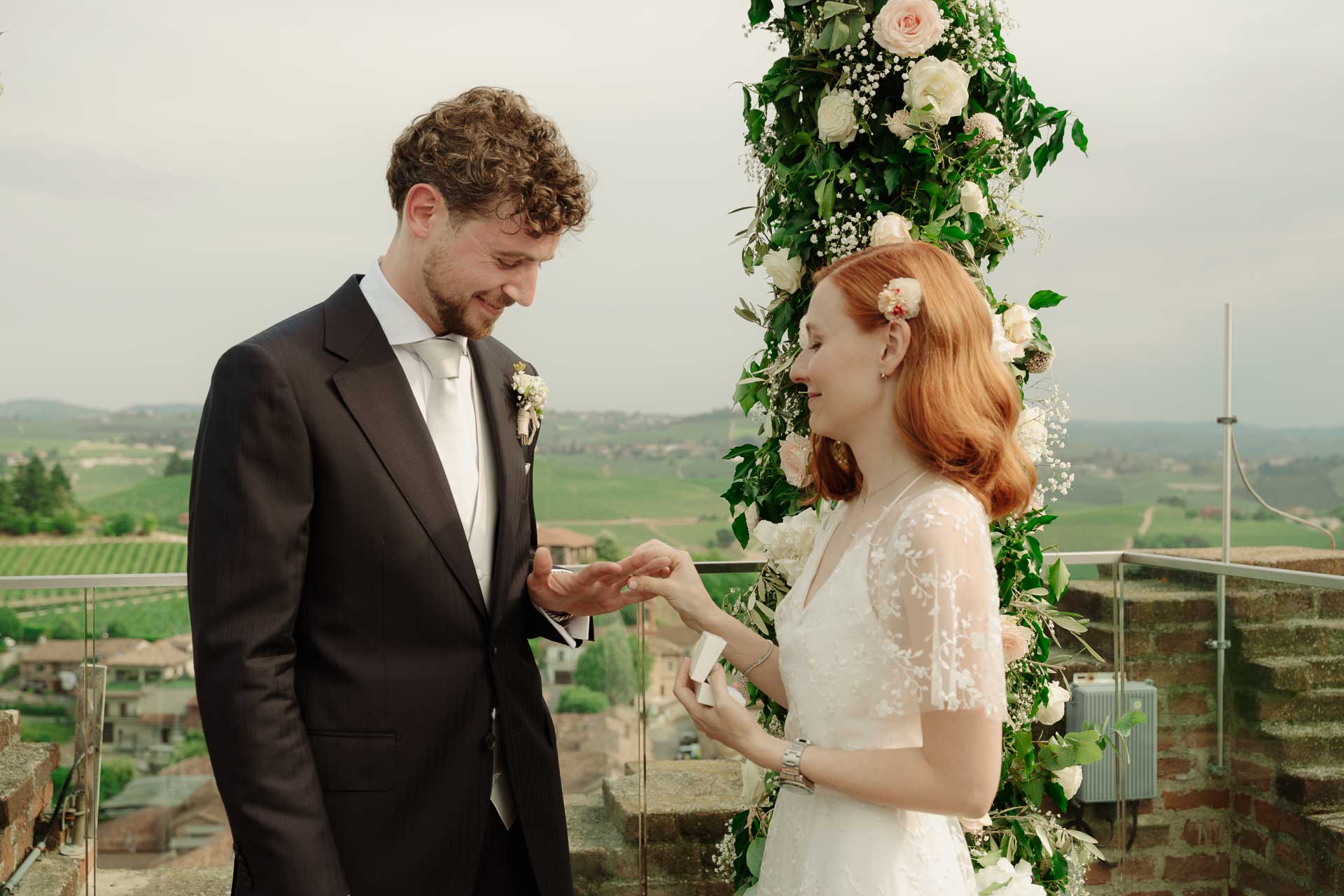 La sposa infila la fede allo sposo, sopra i tetti e le vigne