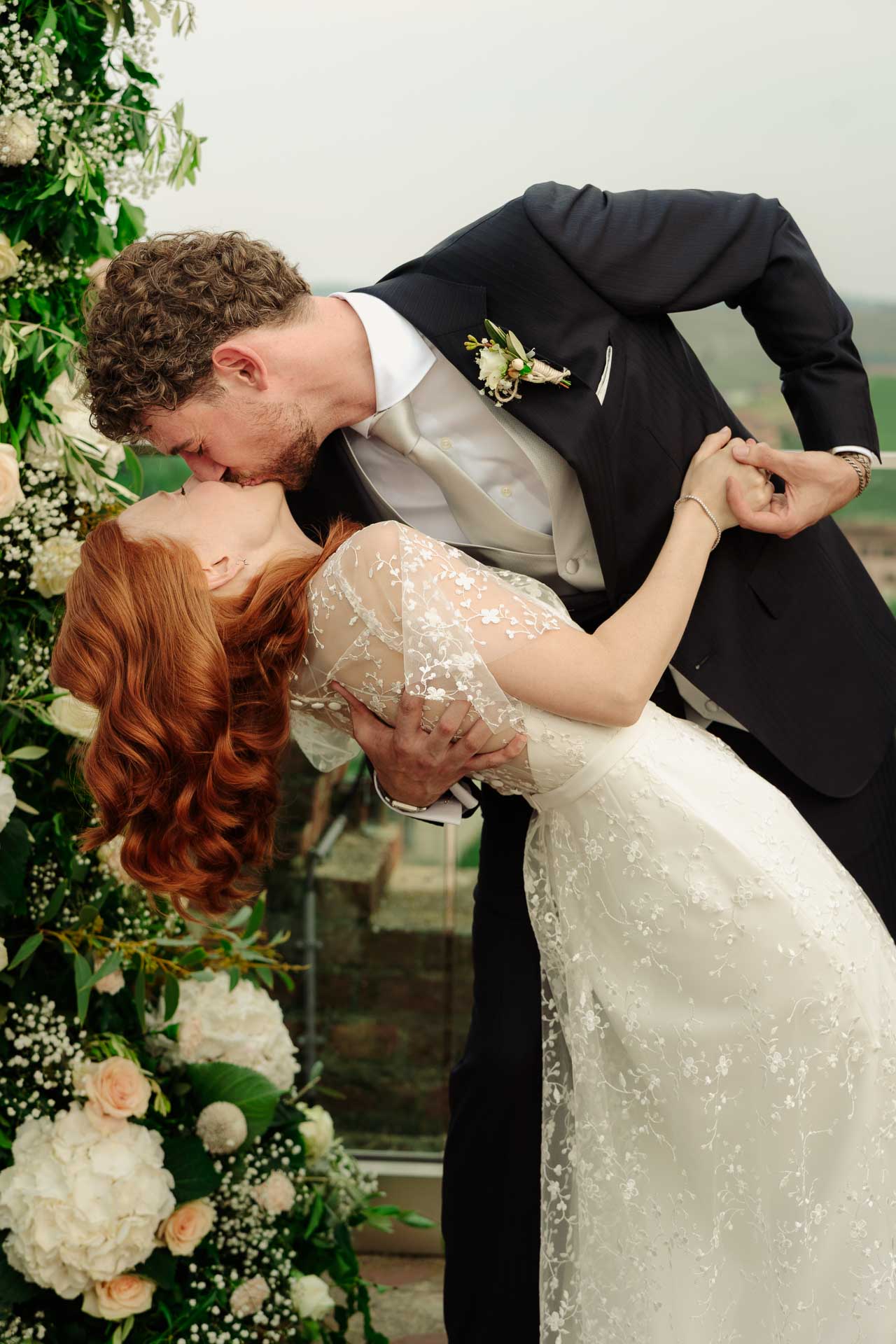 Il casquè: lo sposo piega all'indietro la sposa e la bacia, accanto all'arco di fiori
