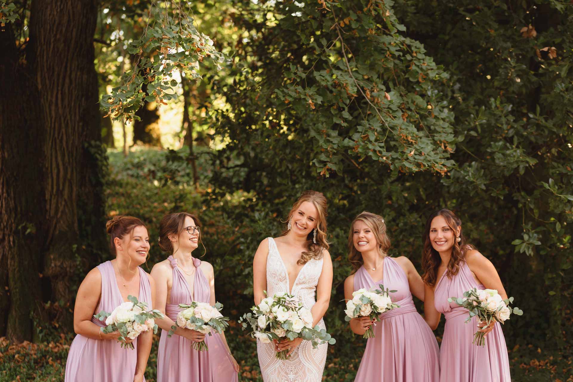 La sposa e le damigelle in rosa tra gli alberi del parco
