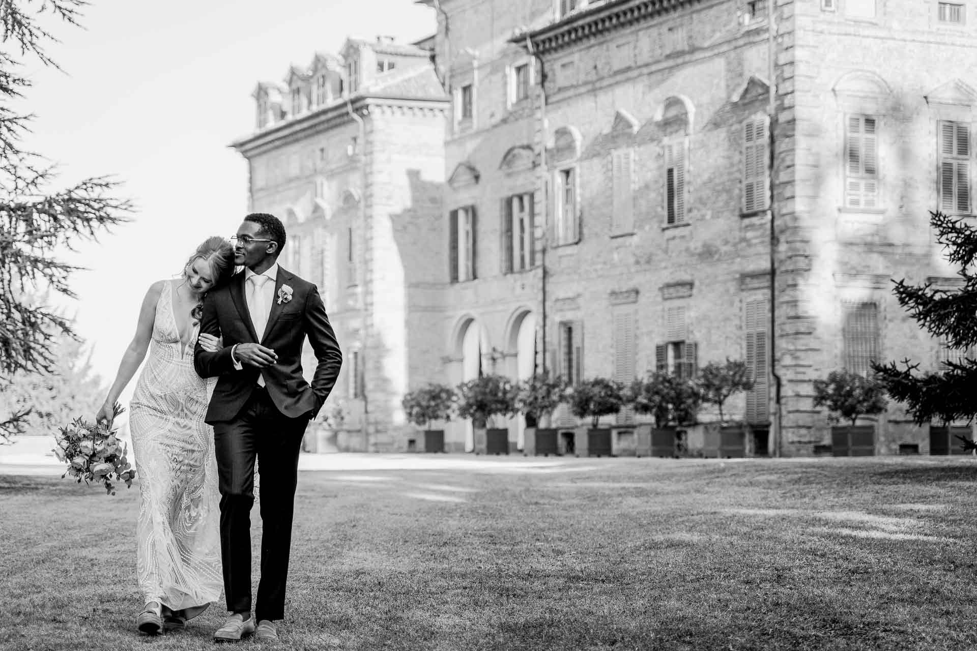 In bianco e nero, la sposa appoggiata allo sposo davanti al castello