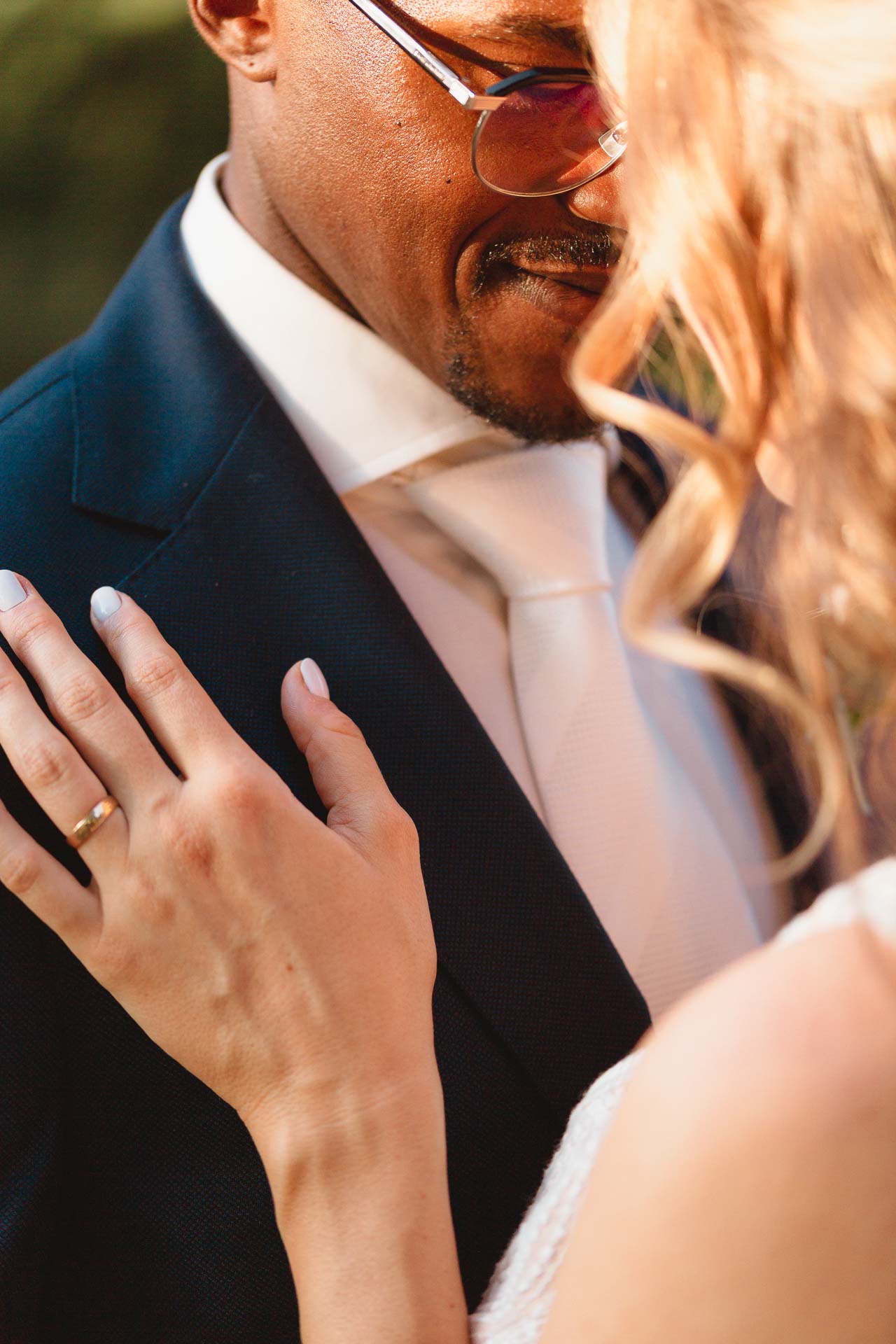 La mano della sposa con la fede sul petto dello sposo